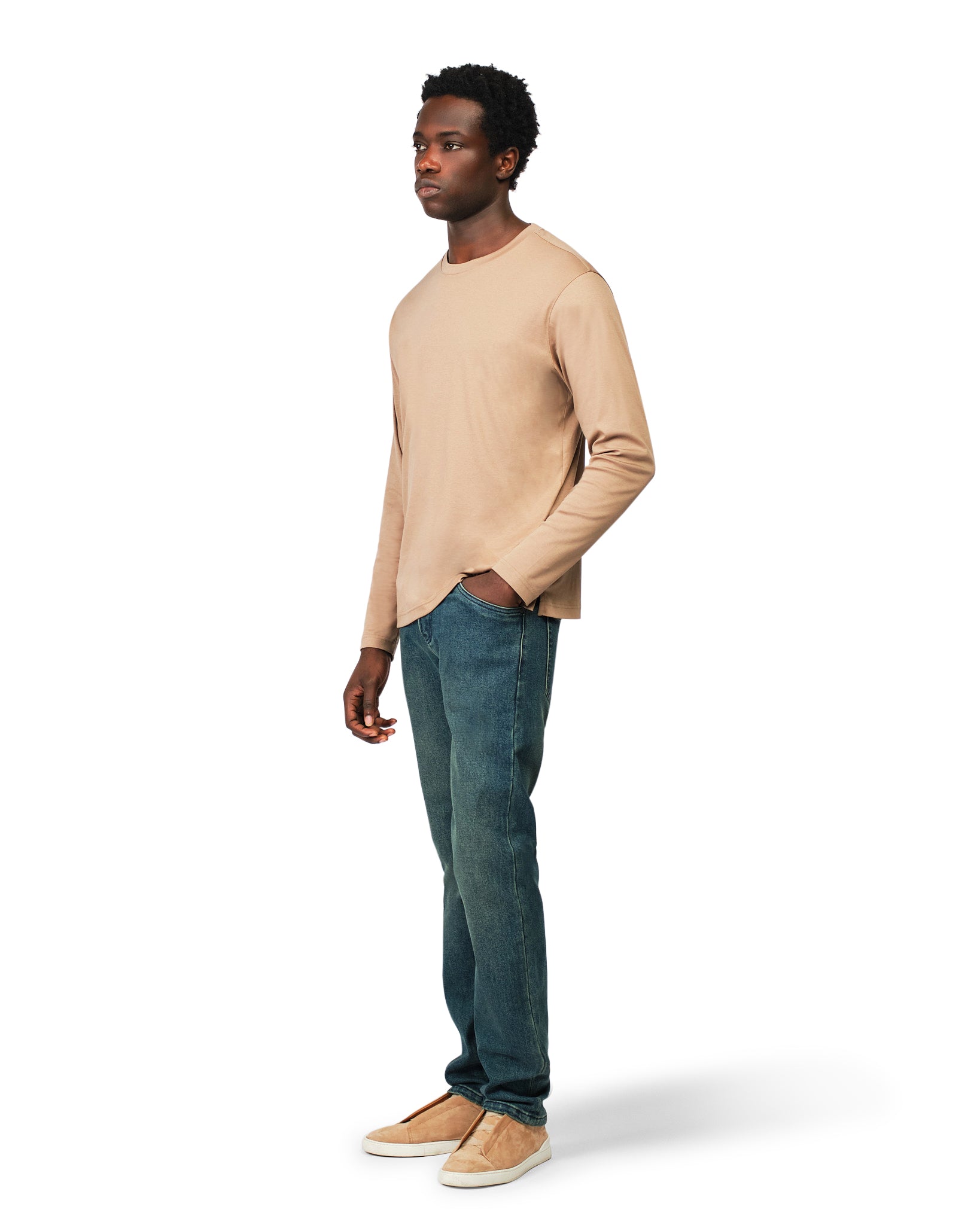 Man wearing a beige sweater and blue jeans on a white background