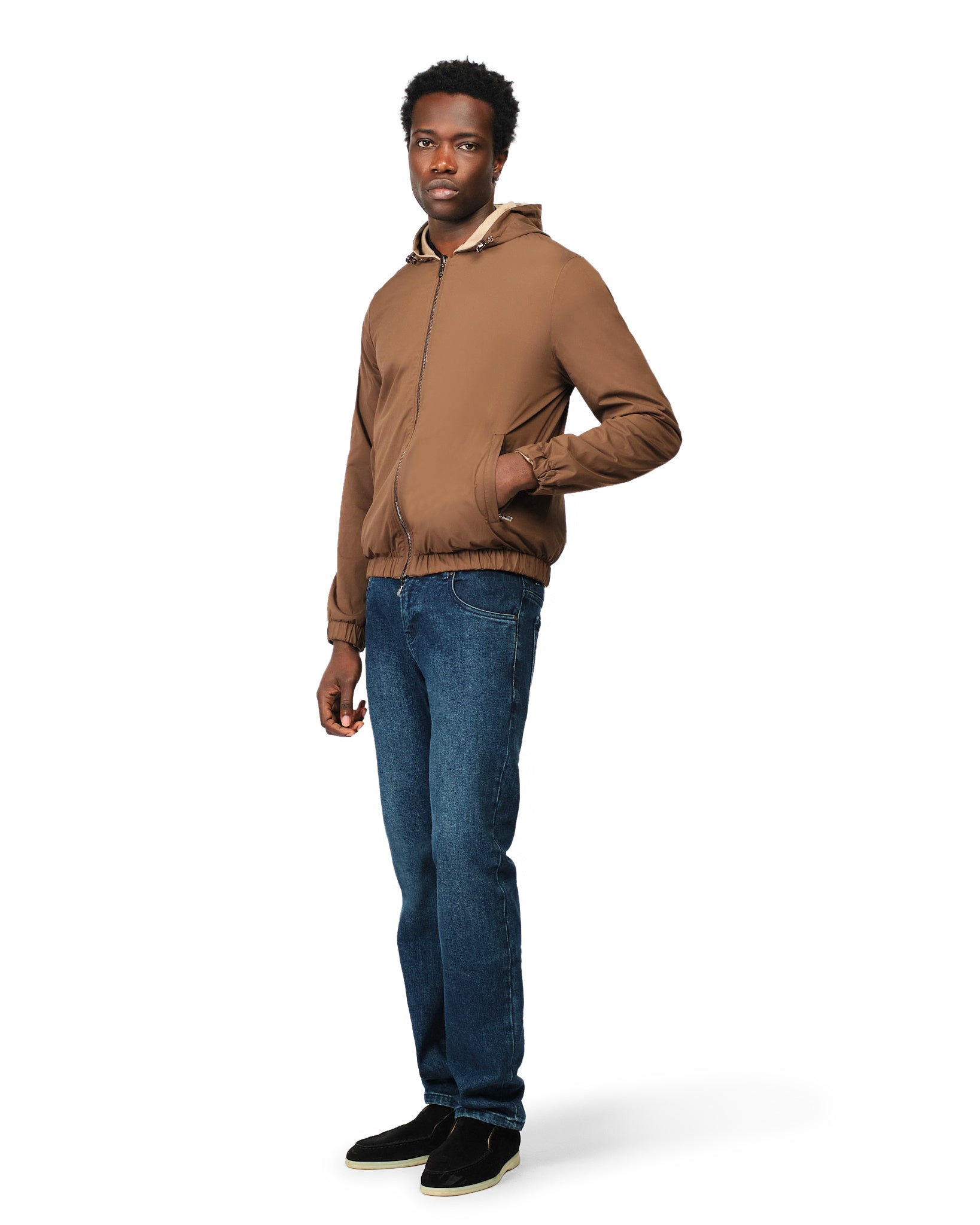 Man wearing a brown jacket and blue jeans on a white background