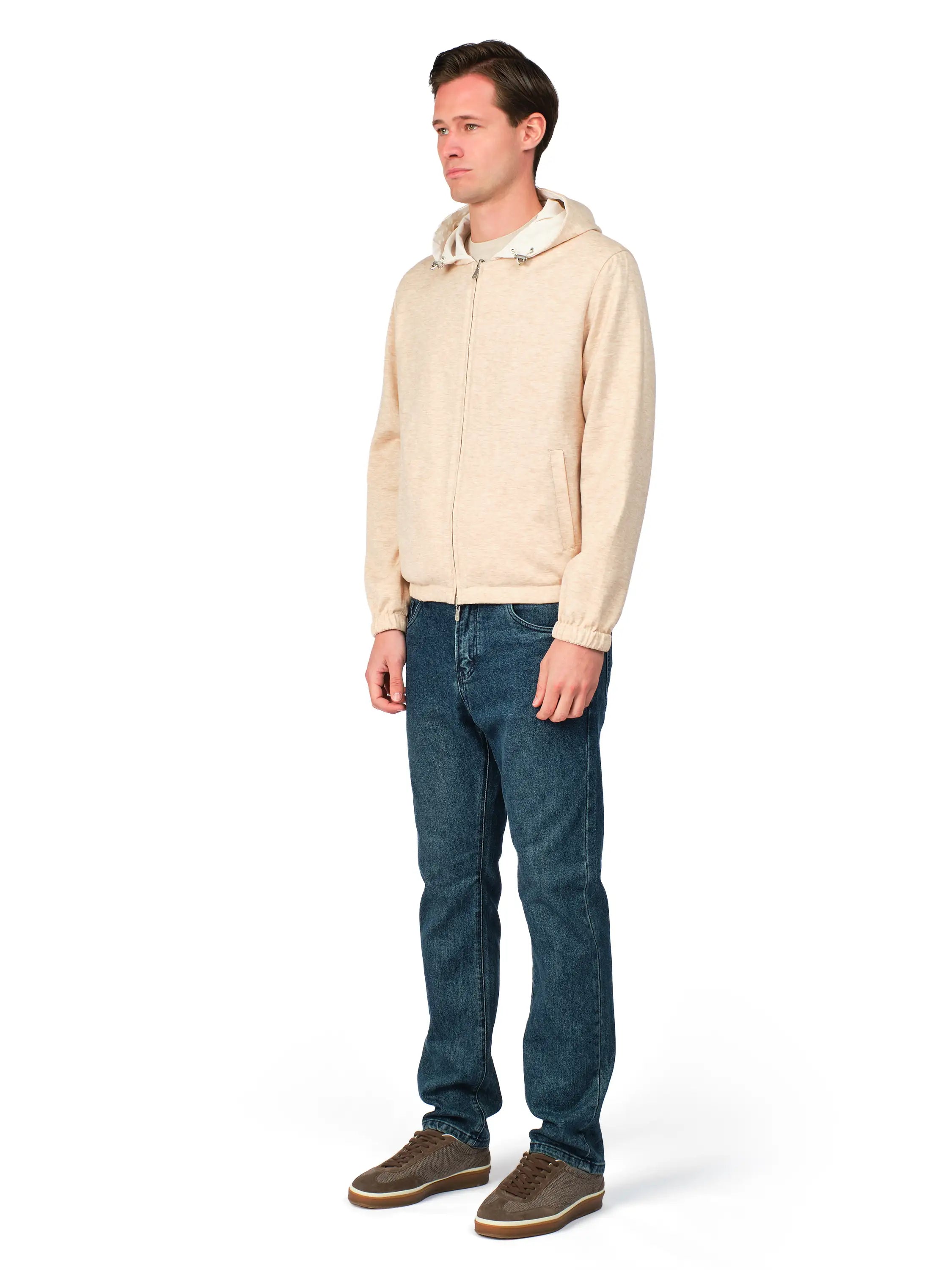 Man wearing a beige jacket and blue jeans on a white background