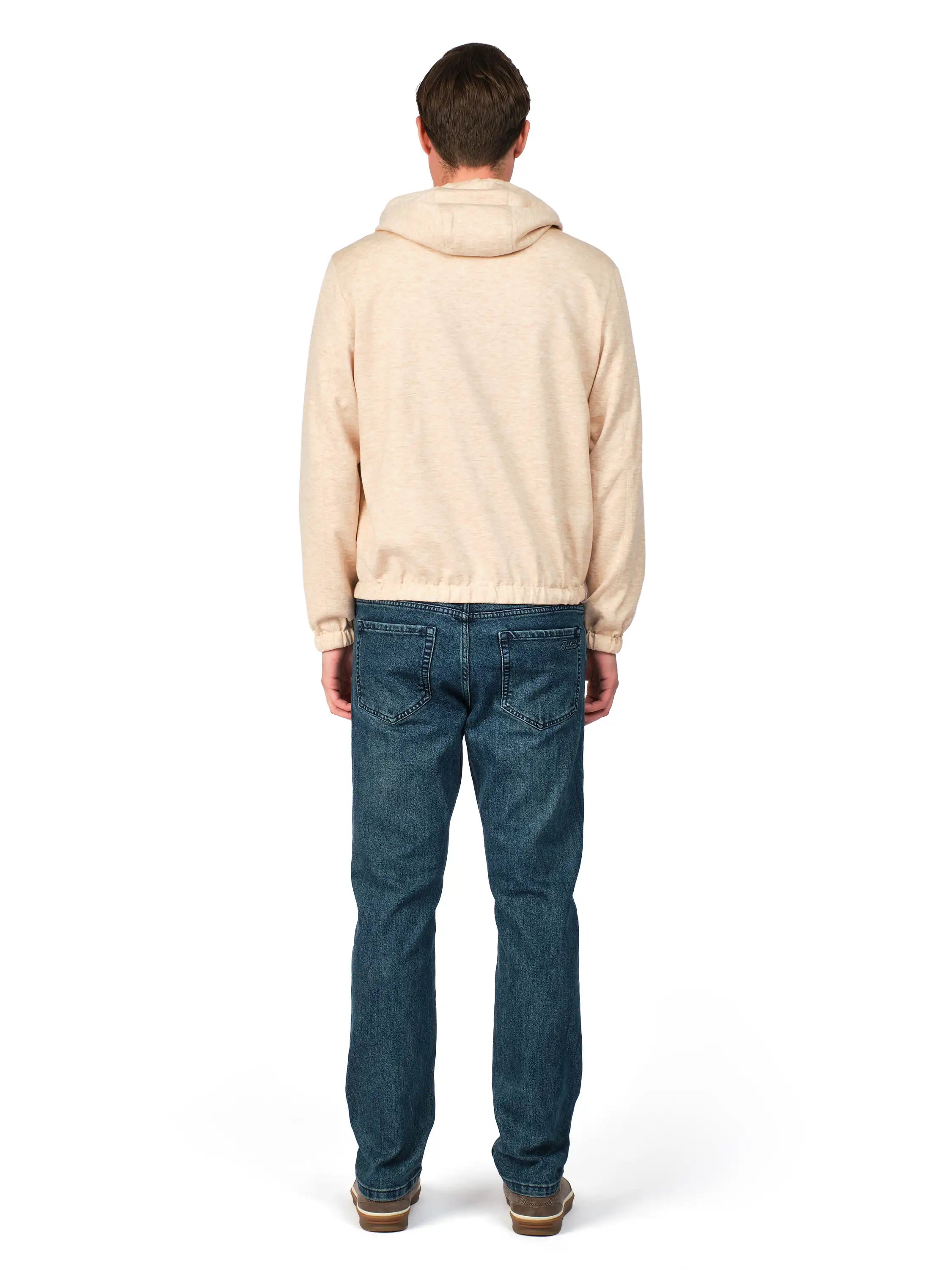 Person wearing a beige hoodie and blue jeans on a white background