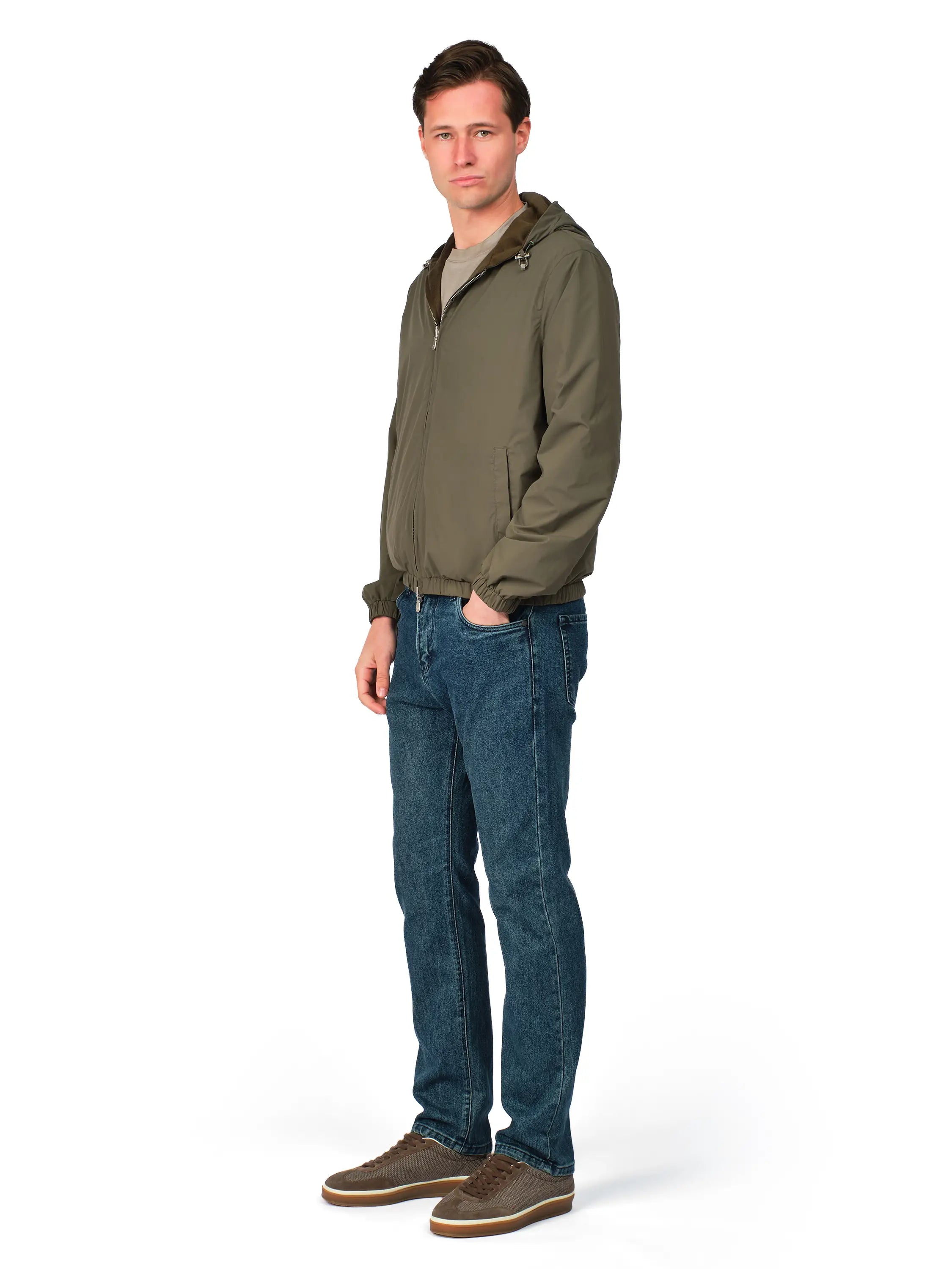 Man wearing a green jacket and blue jeans on a white background