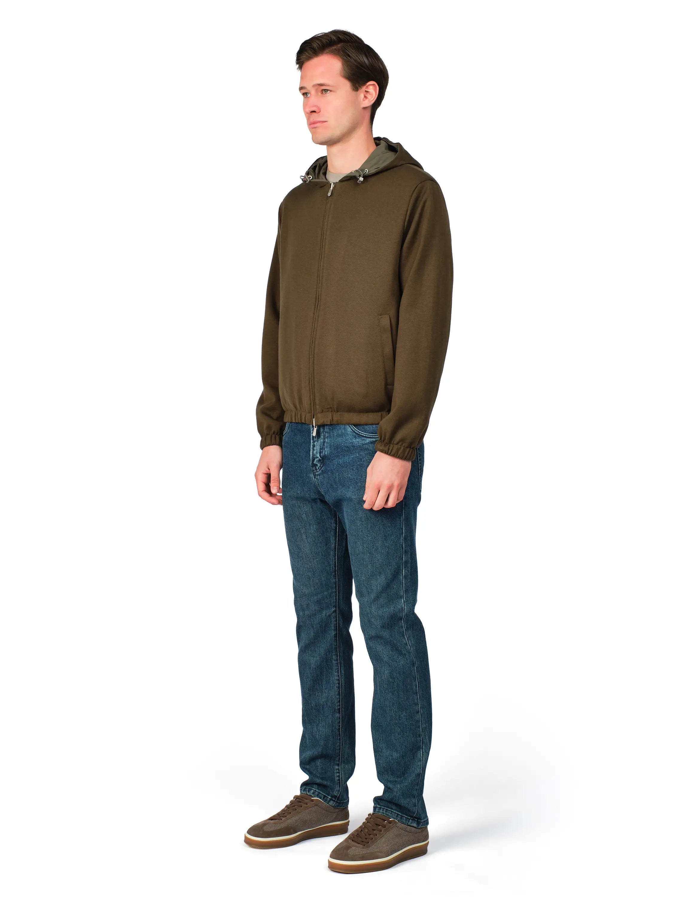 Man wearing a green jacket and blue jeans on a white background