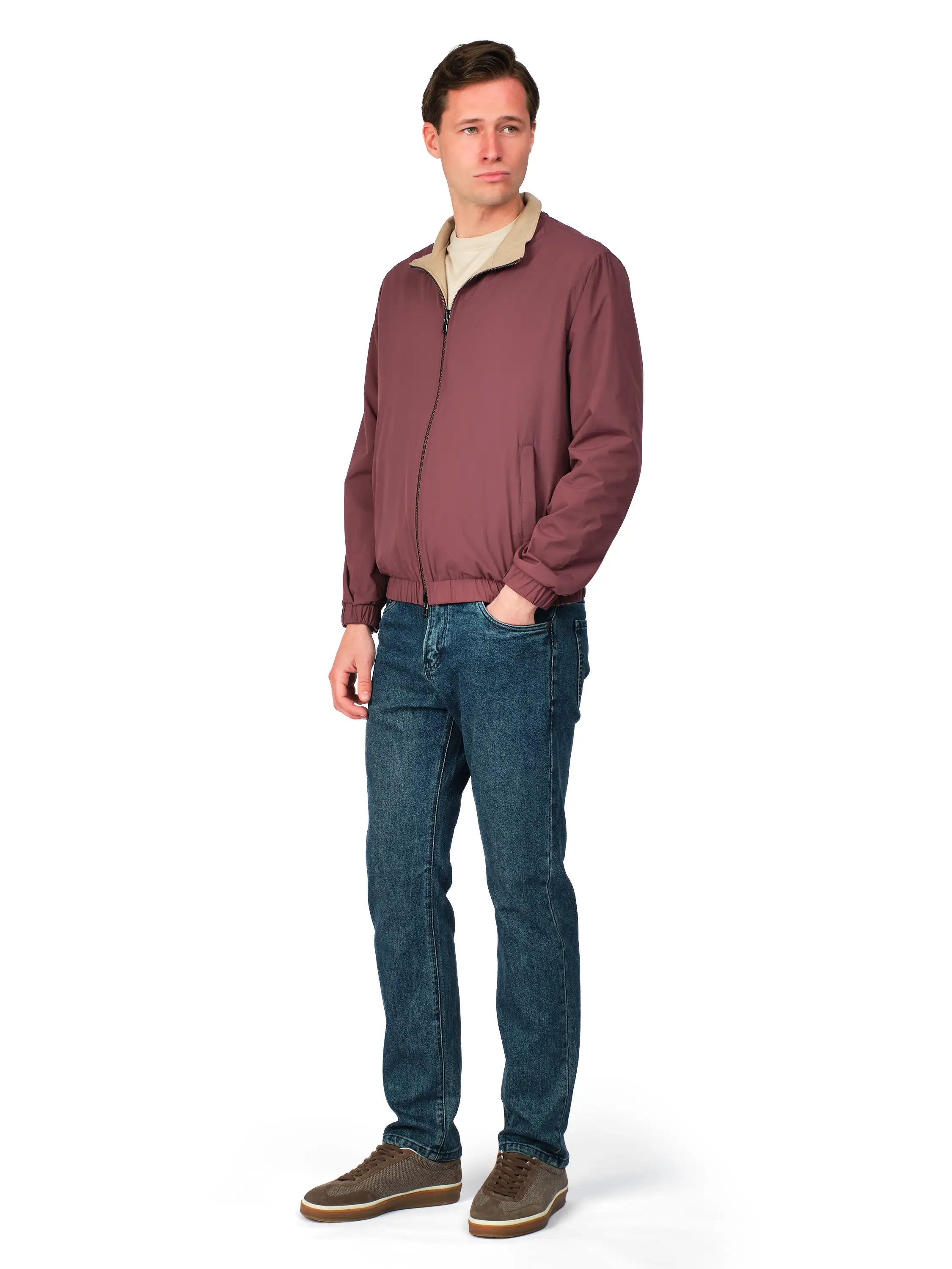 Man wearing a maroon jacket and blue jeans on a white background