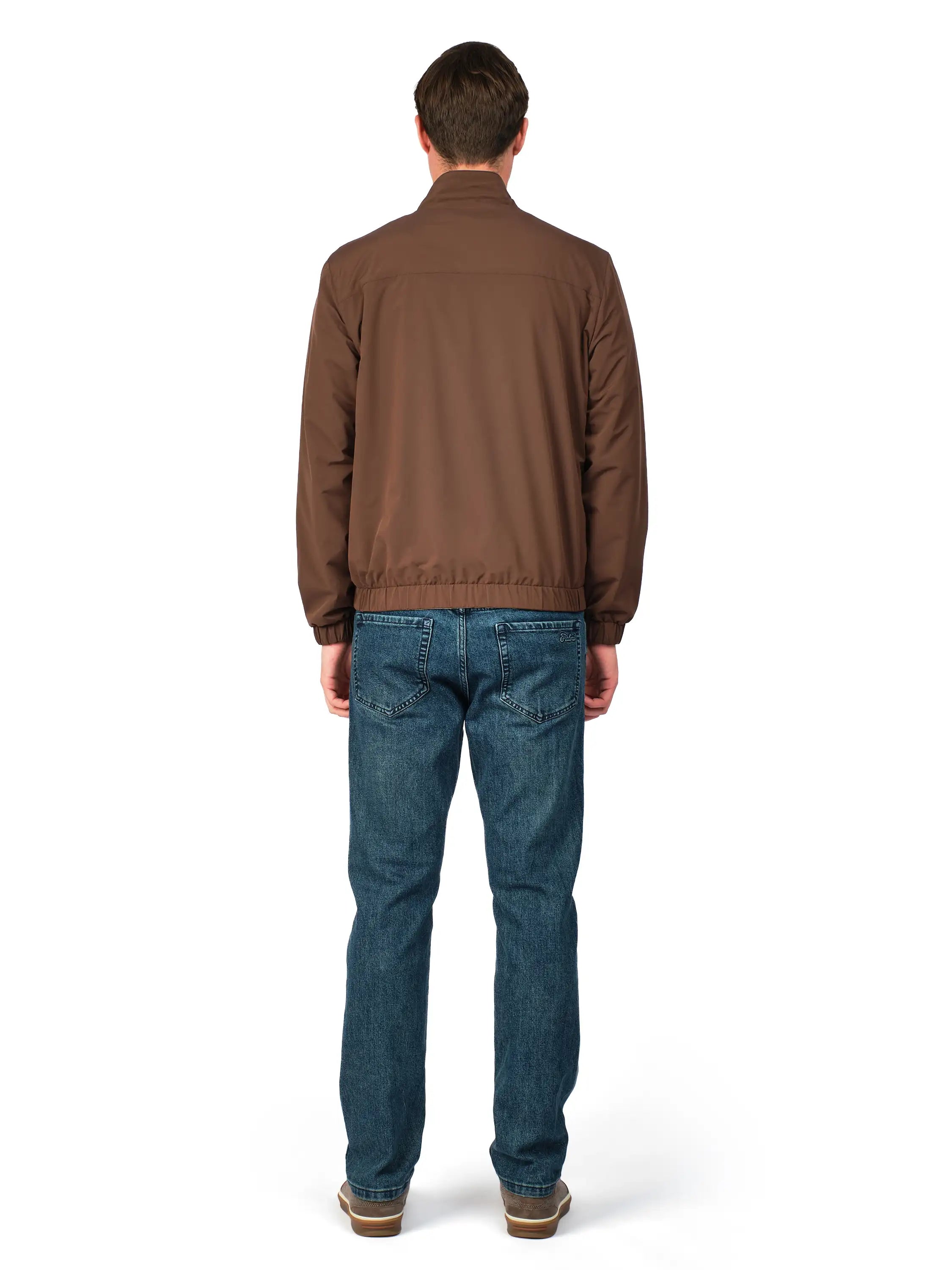 Man wearing a brown jacket and blue jeans on a white background