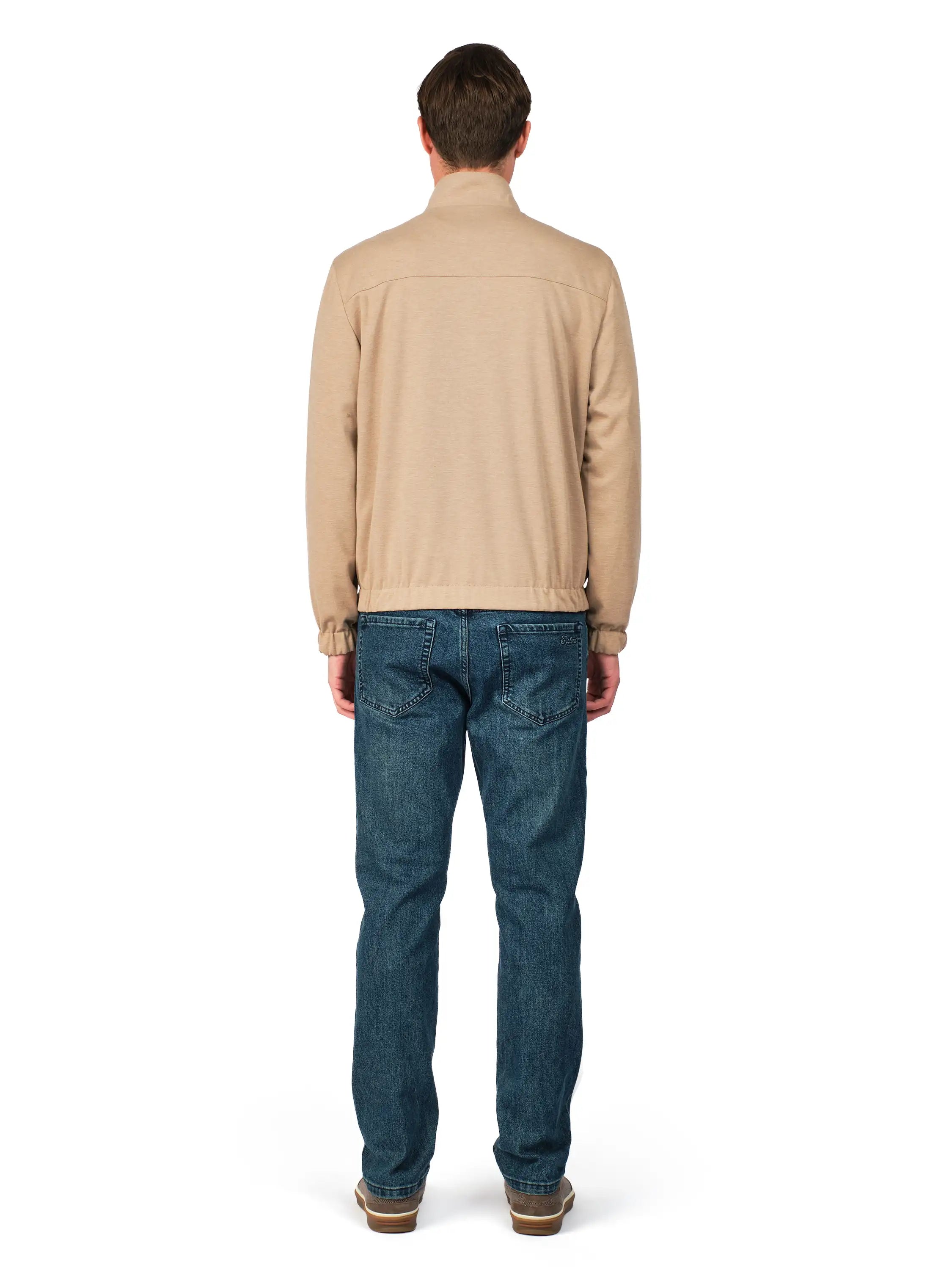 Man wearing a beige sweater and blue jeans on a white background