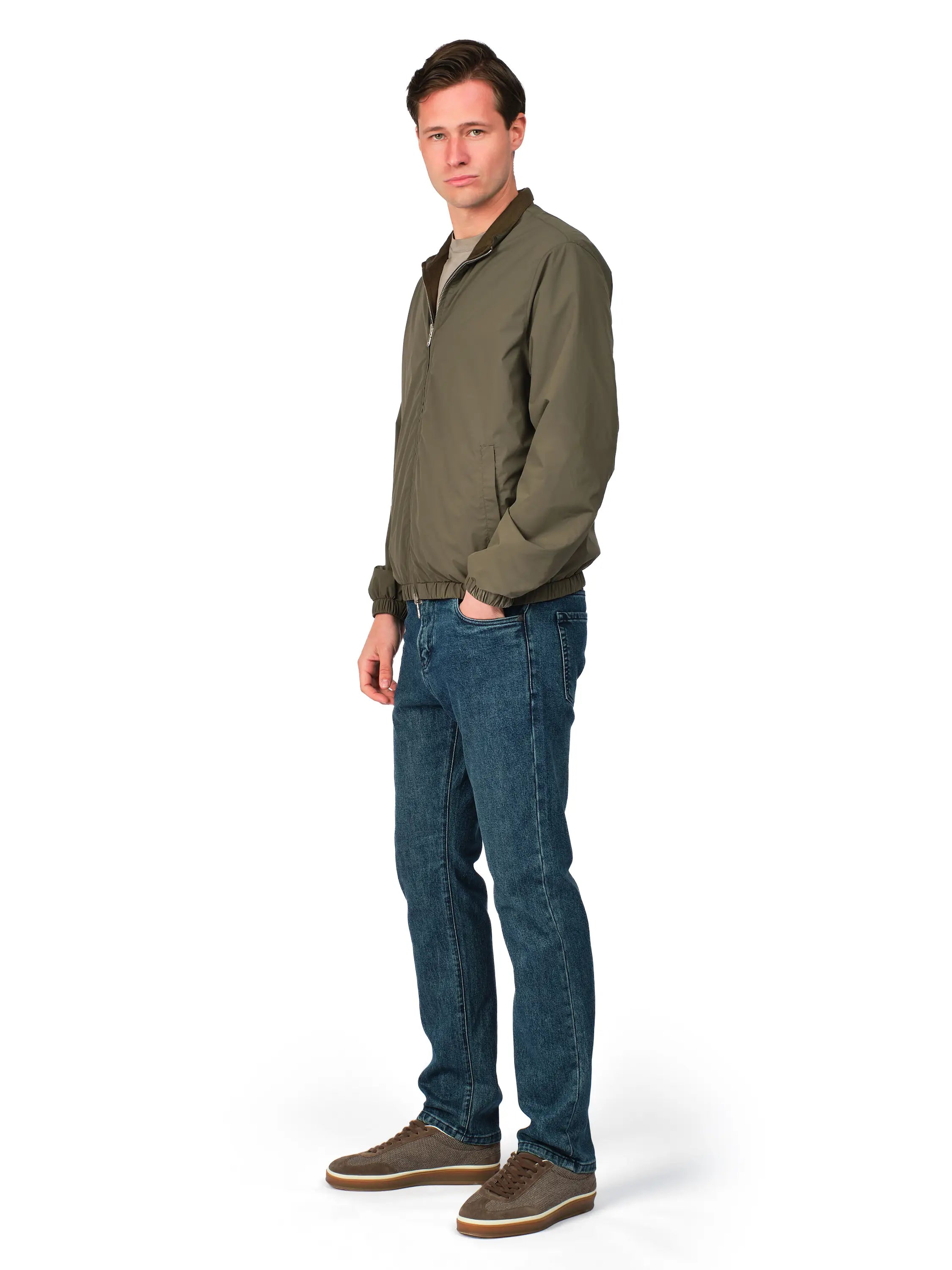 Man wearing a green jacket and blue jeans on a white background