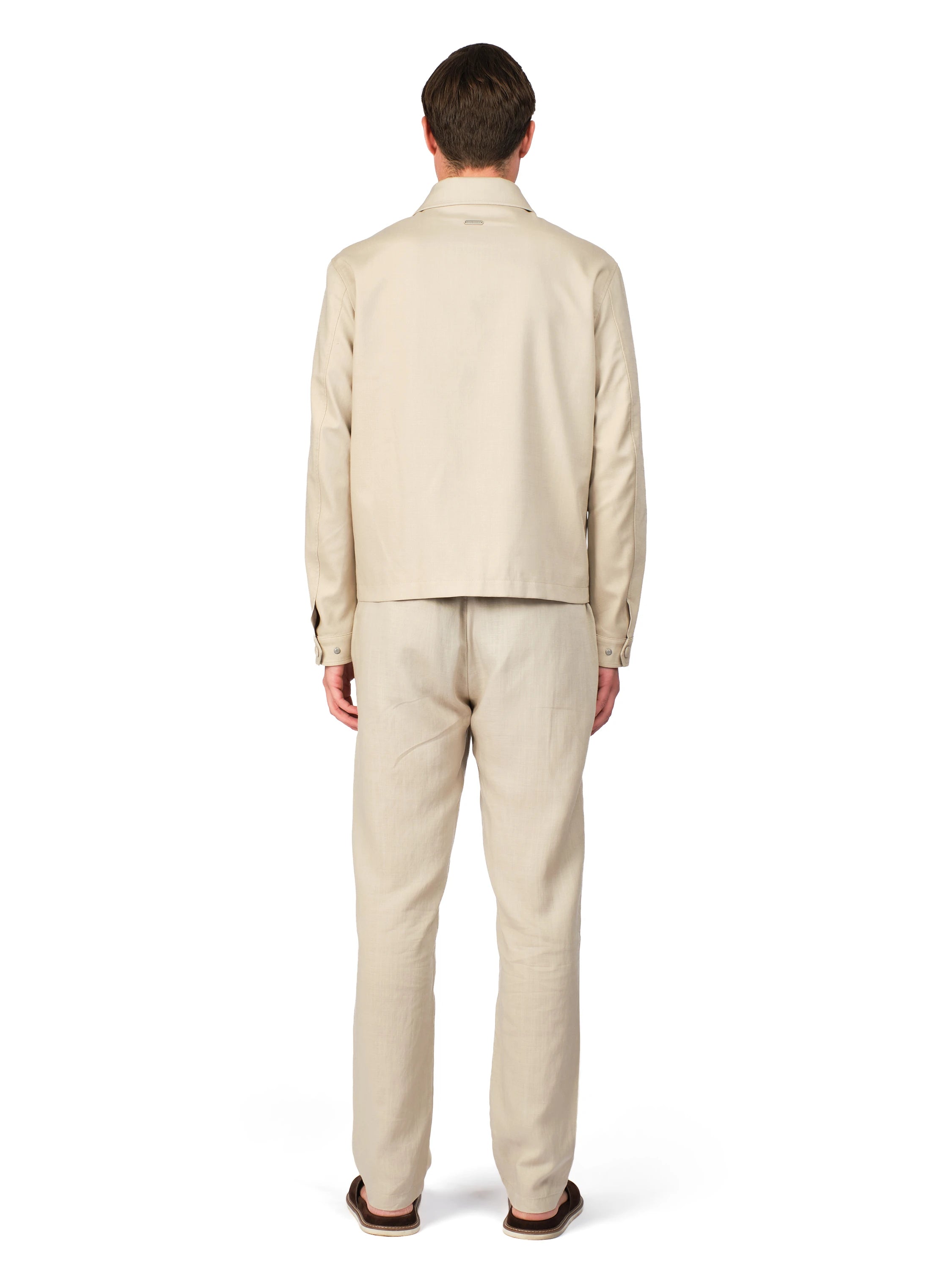 Man wearing a beige suit standing against a white background