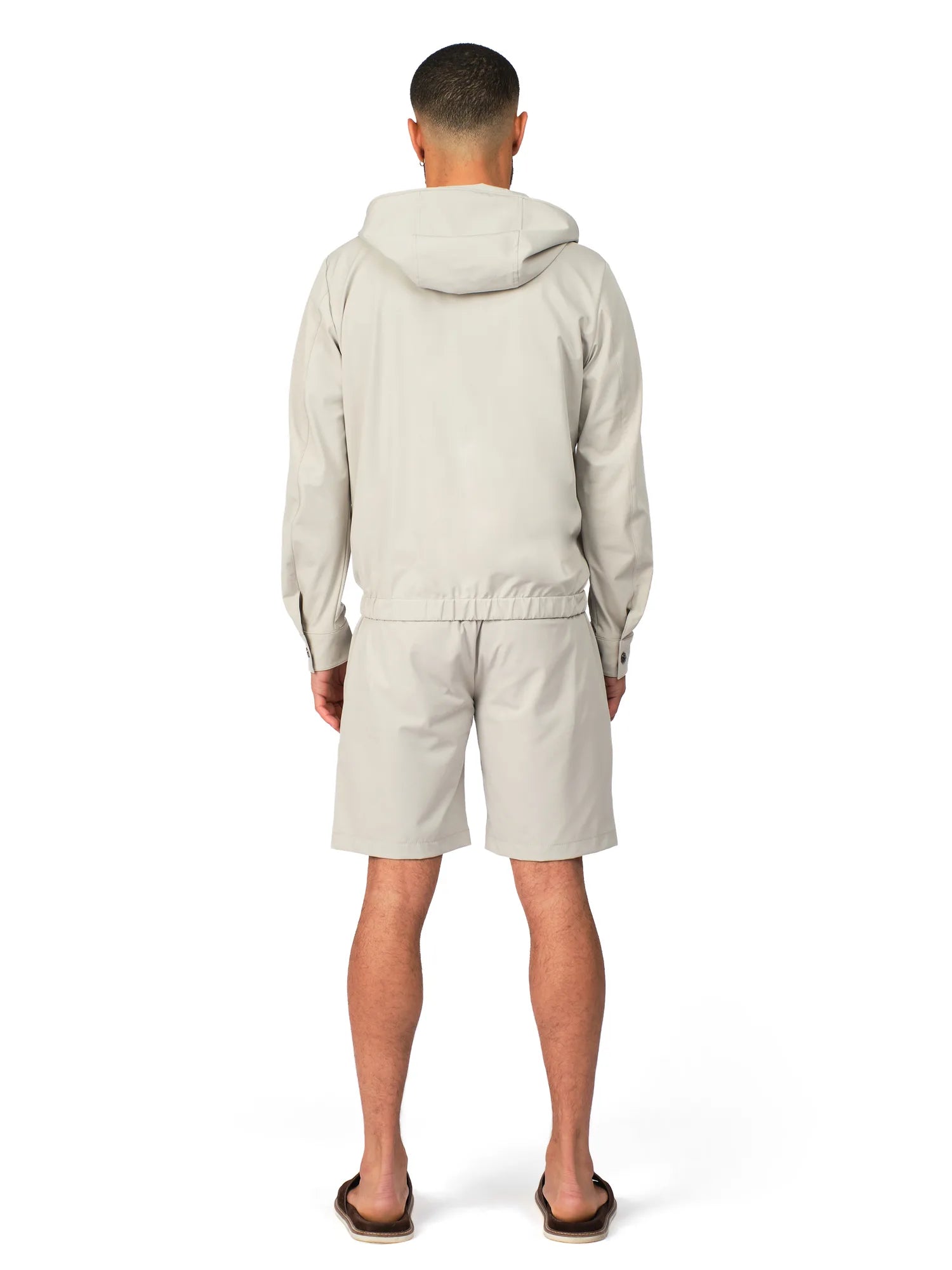 Person wearing a light gray hoodie and shorts set on a white background