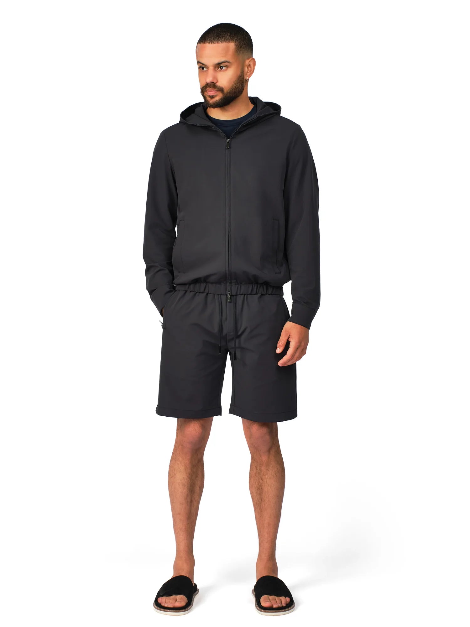 Man wearing a black hoodie and shorts set on a white background