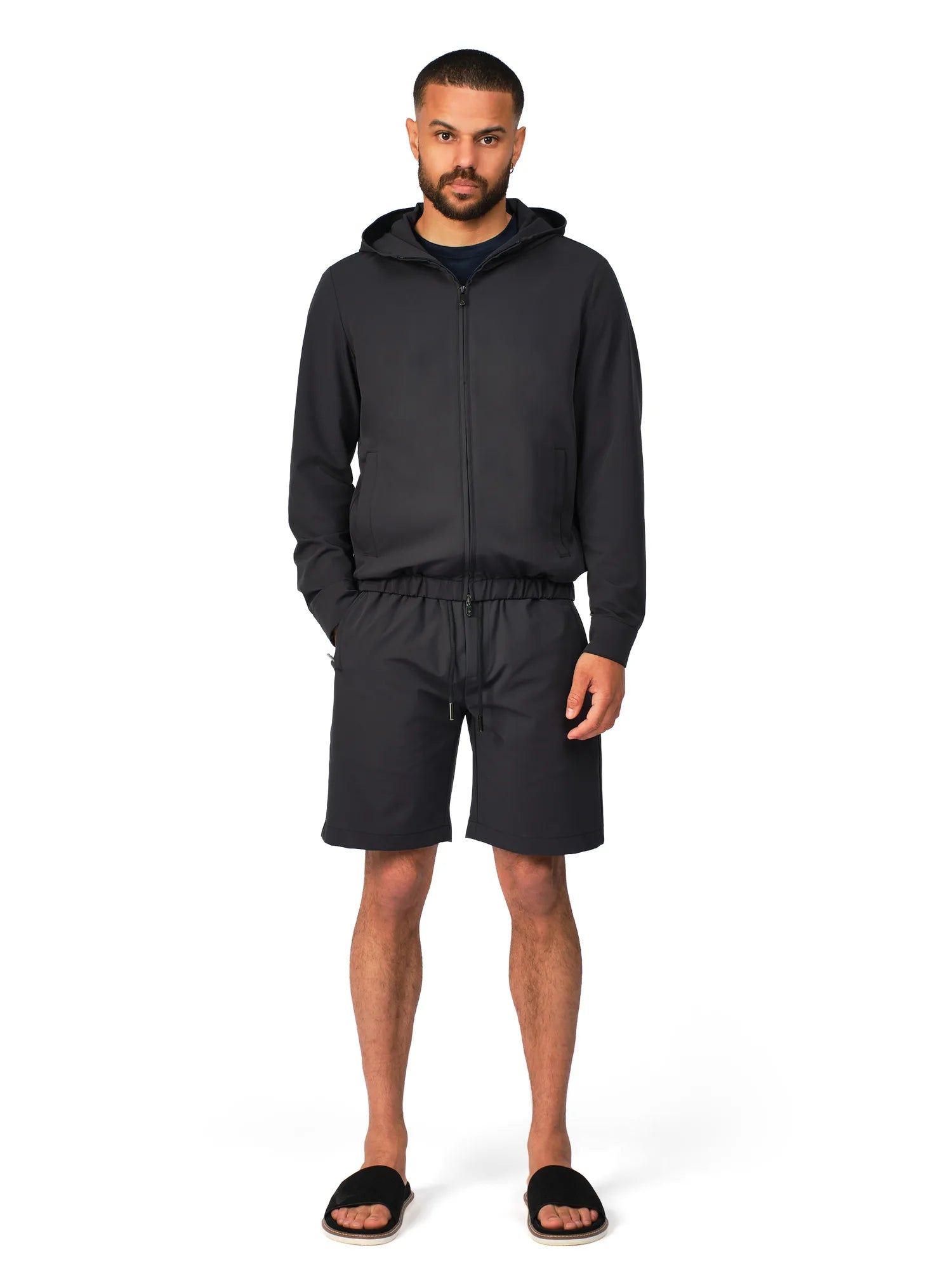 Man wearing a black hoodie and shorts set on a white background