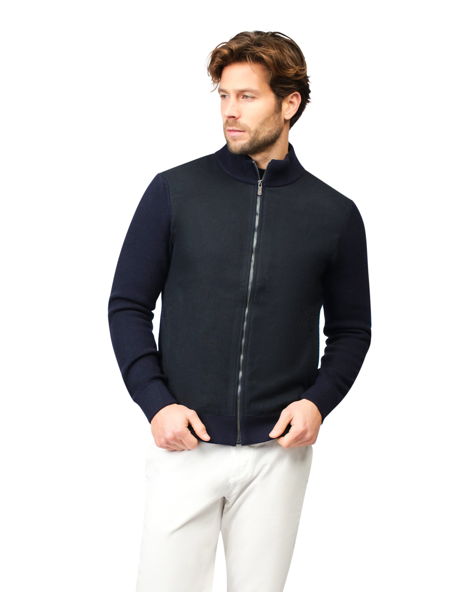 Man wearing a navy blue zip-up sweater over a white shirt on a white background