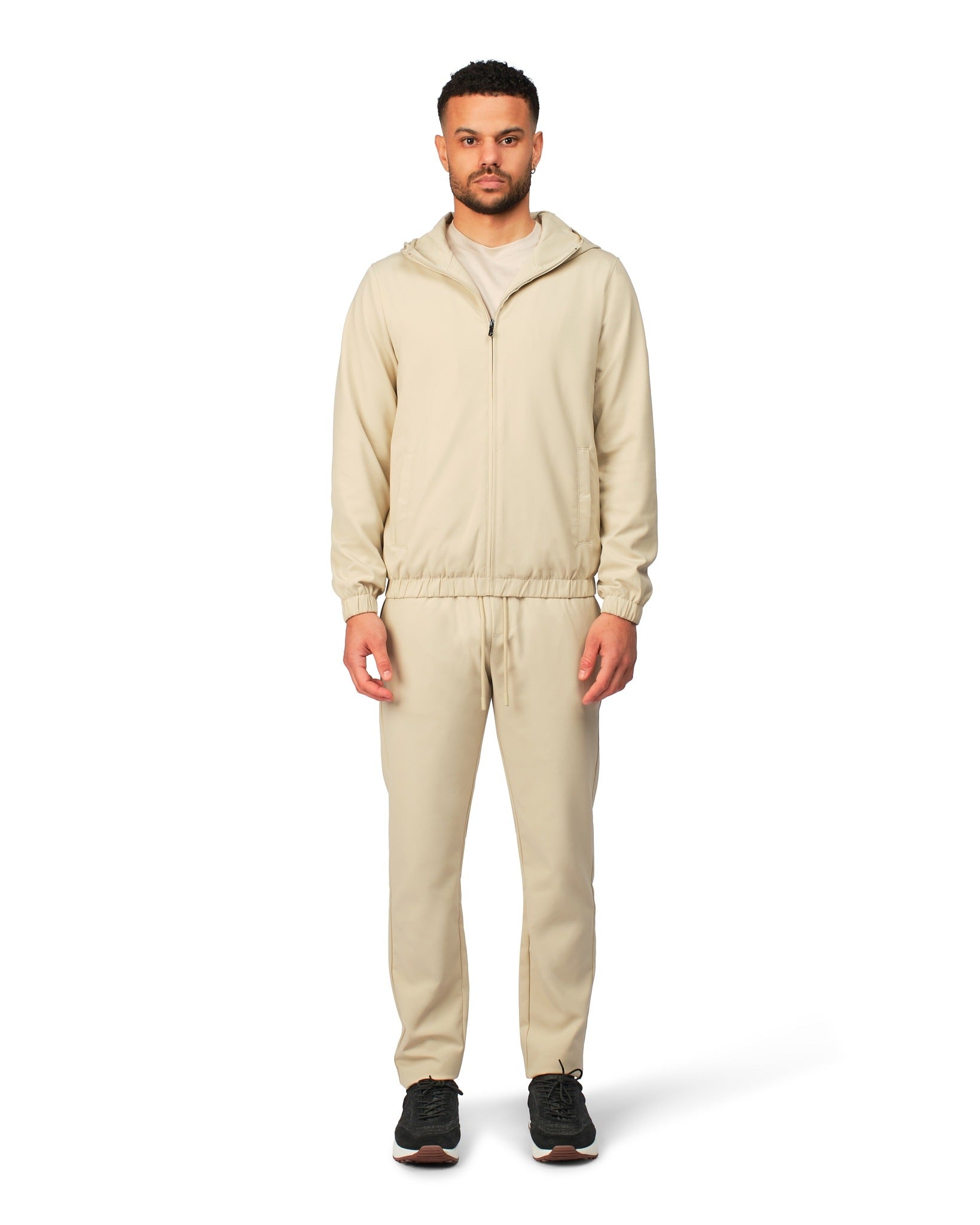 Man wearing a beige tracksuit on a white background