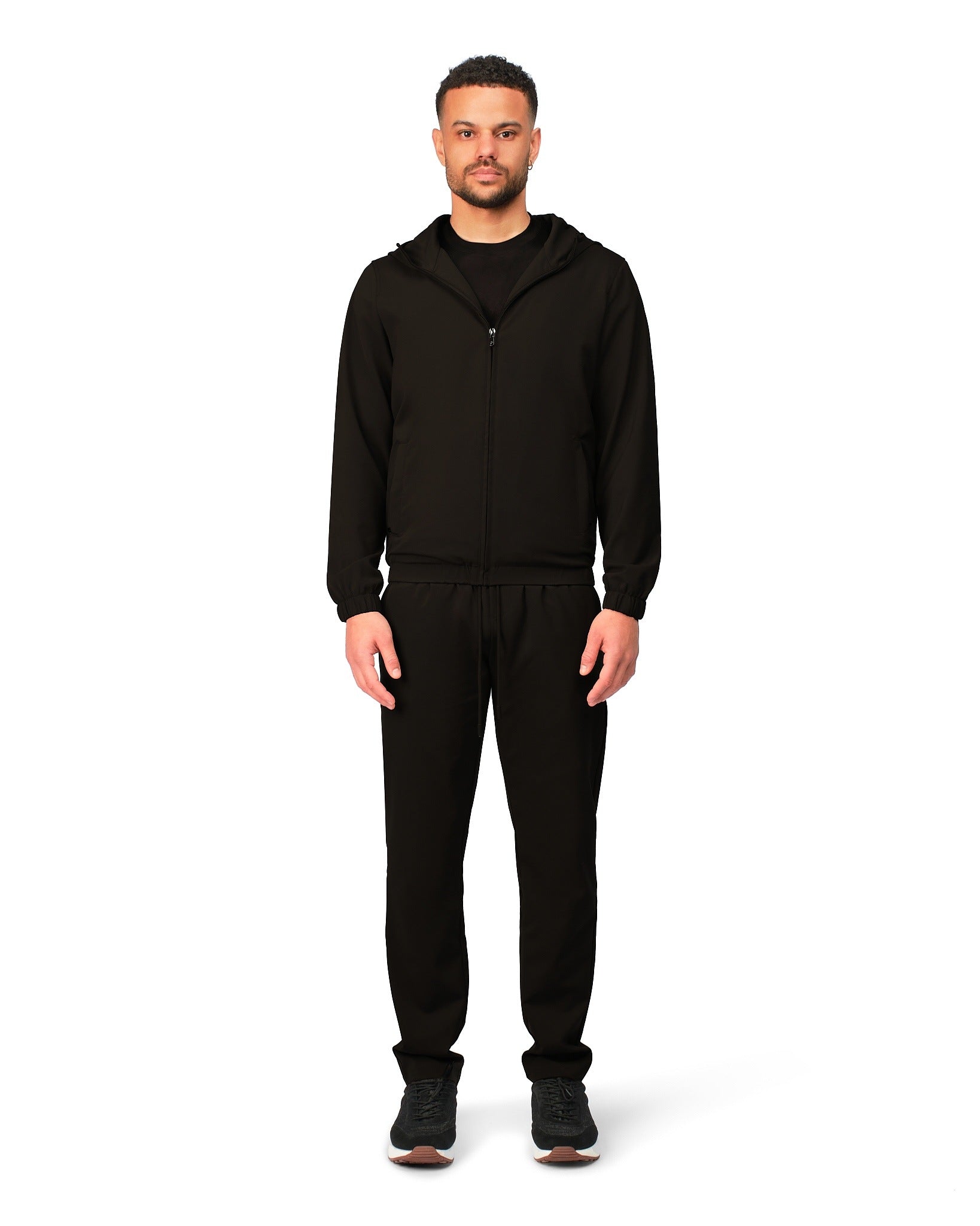 Man wearing a black hoodie and pants on a white background