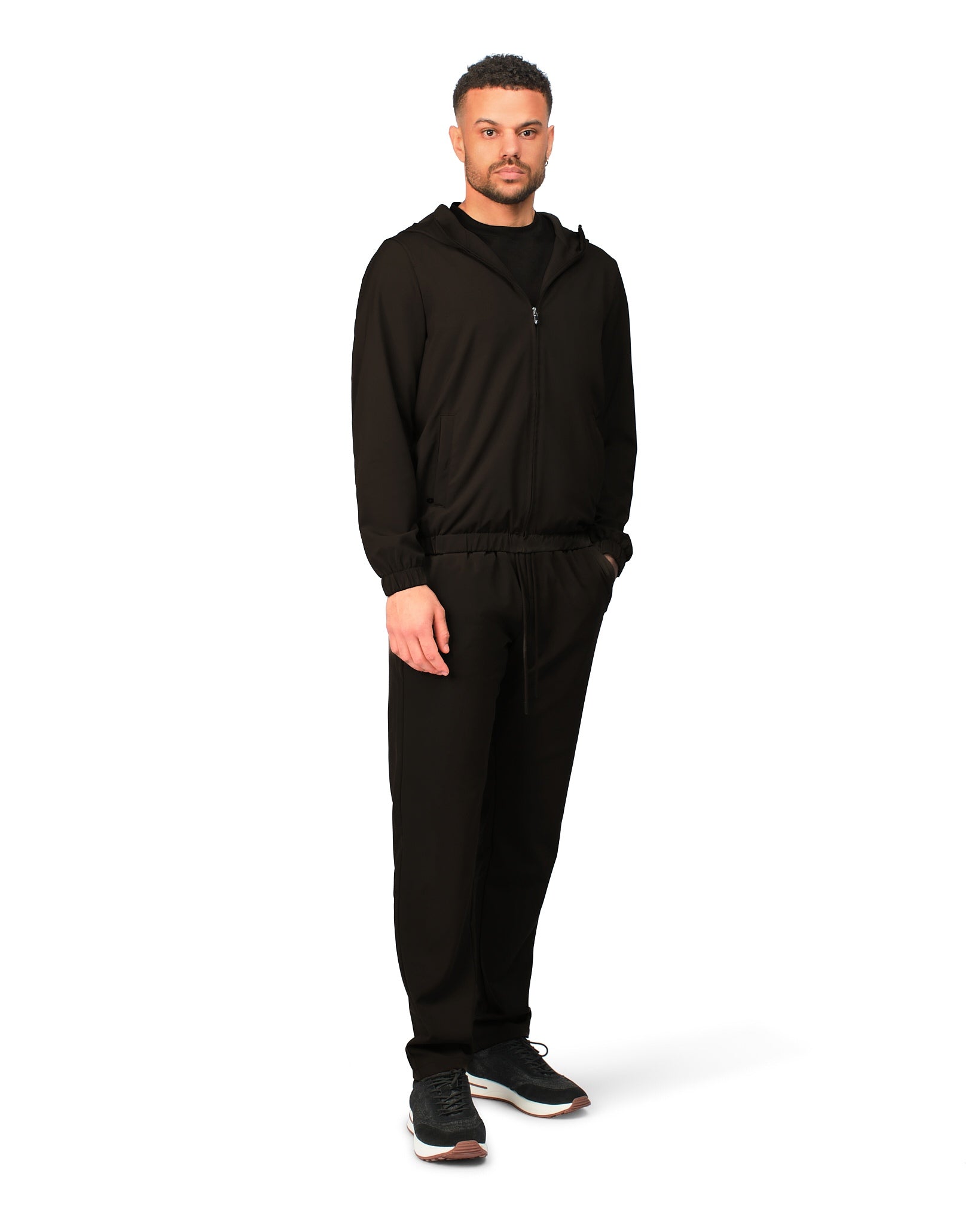 Man wearing a black hoodie and pants on a white background