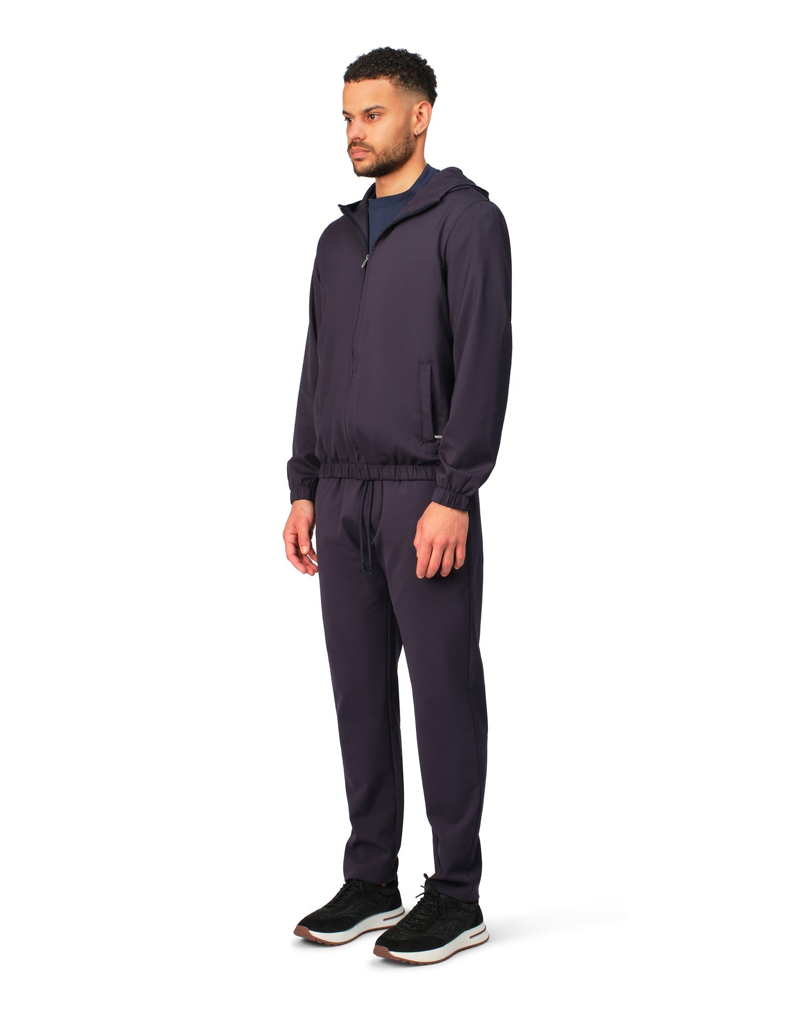 Man wearing a dark tracksuit on a white background
