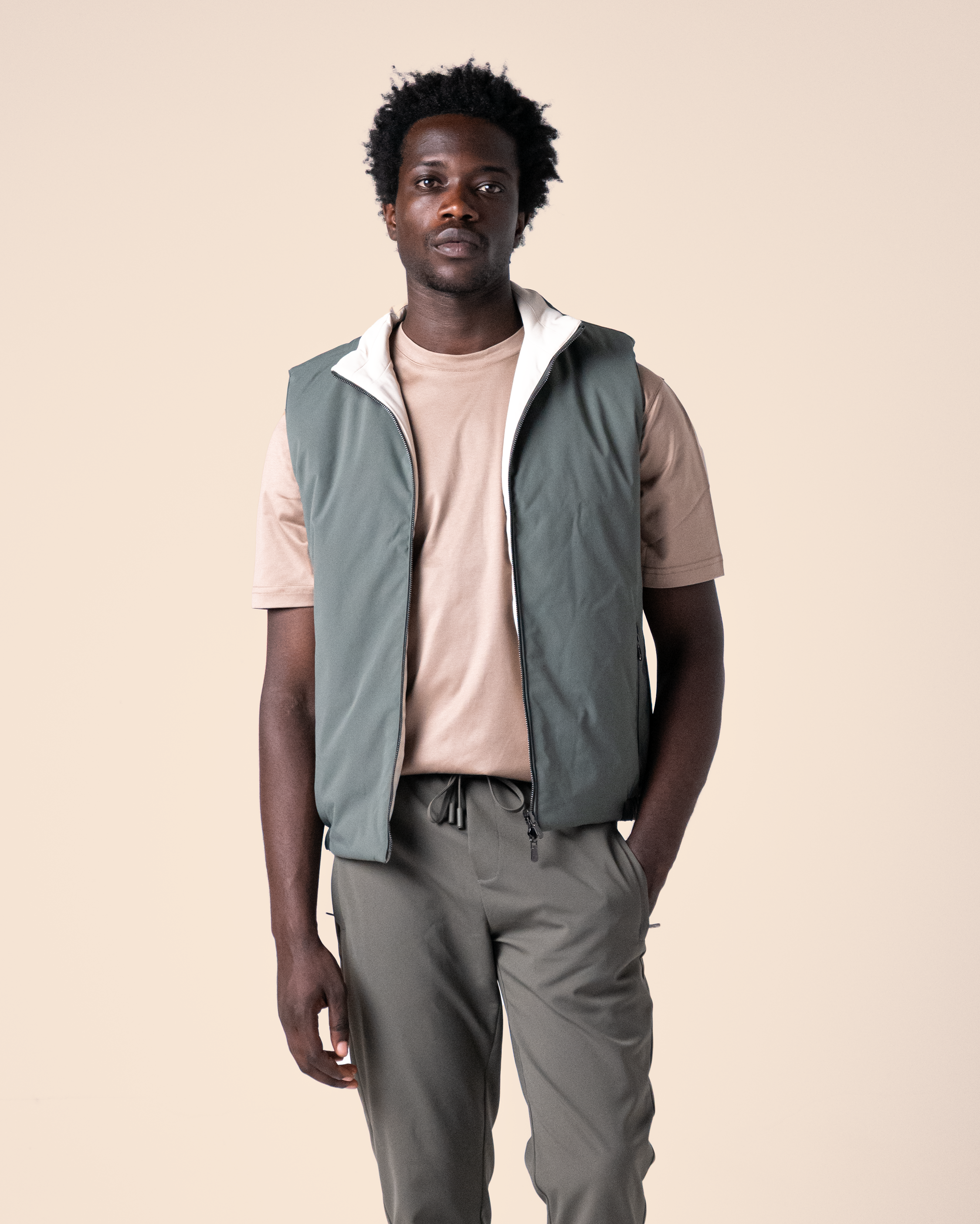 Man wearing a green vest over a beige shirt on a beige background