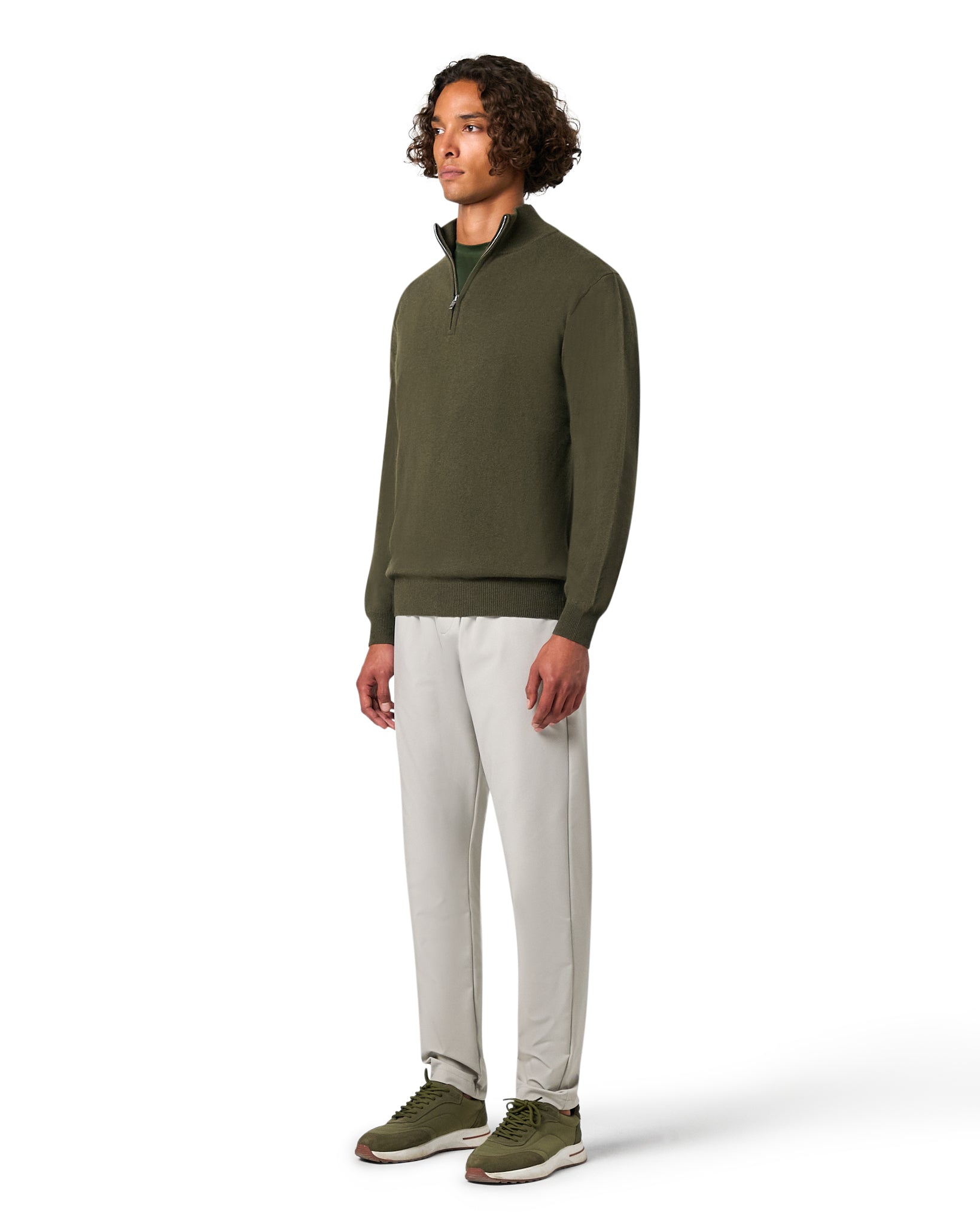Man wearing a green sweater and white pants on a white background