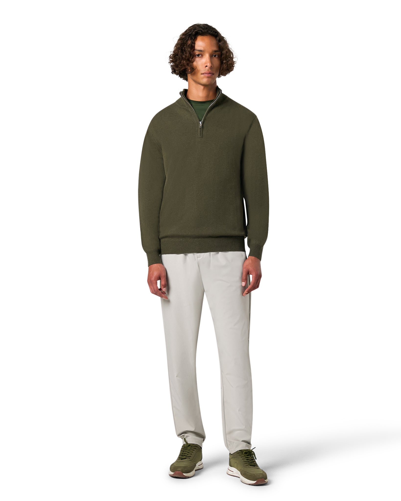 Man wearing a green sweater and beige pants on a white background