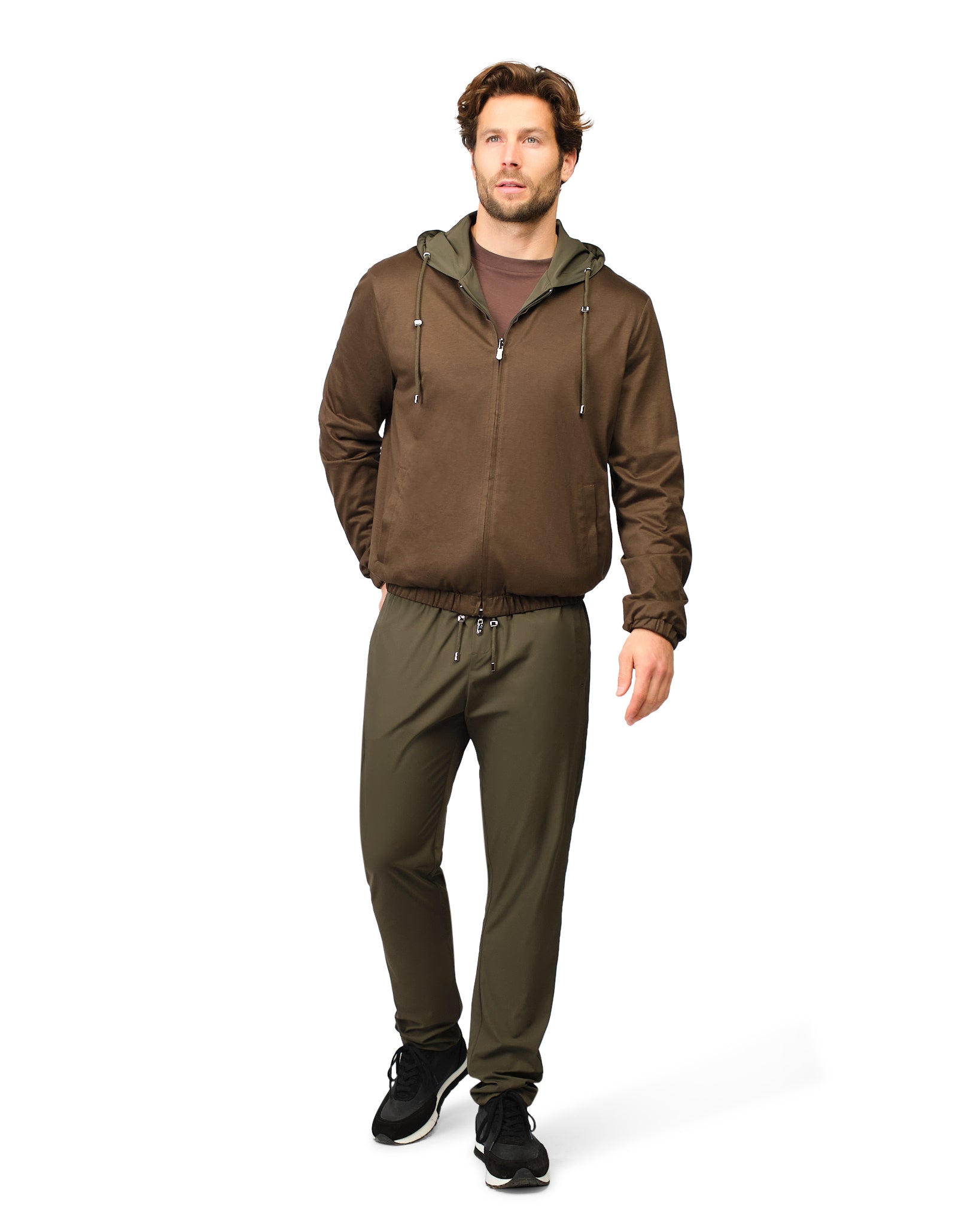 Man wearing a brown jacket and green pants on a white background