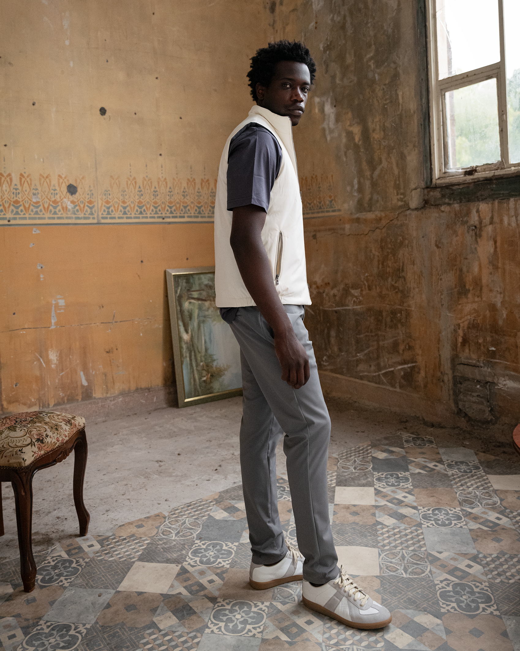 Man standing in a room with peeling paint and a window