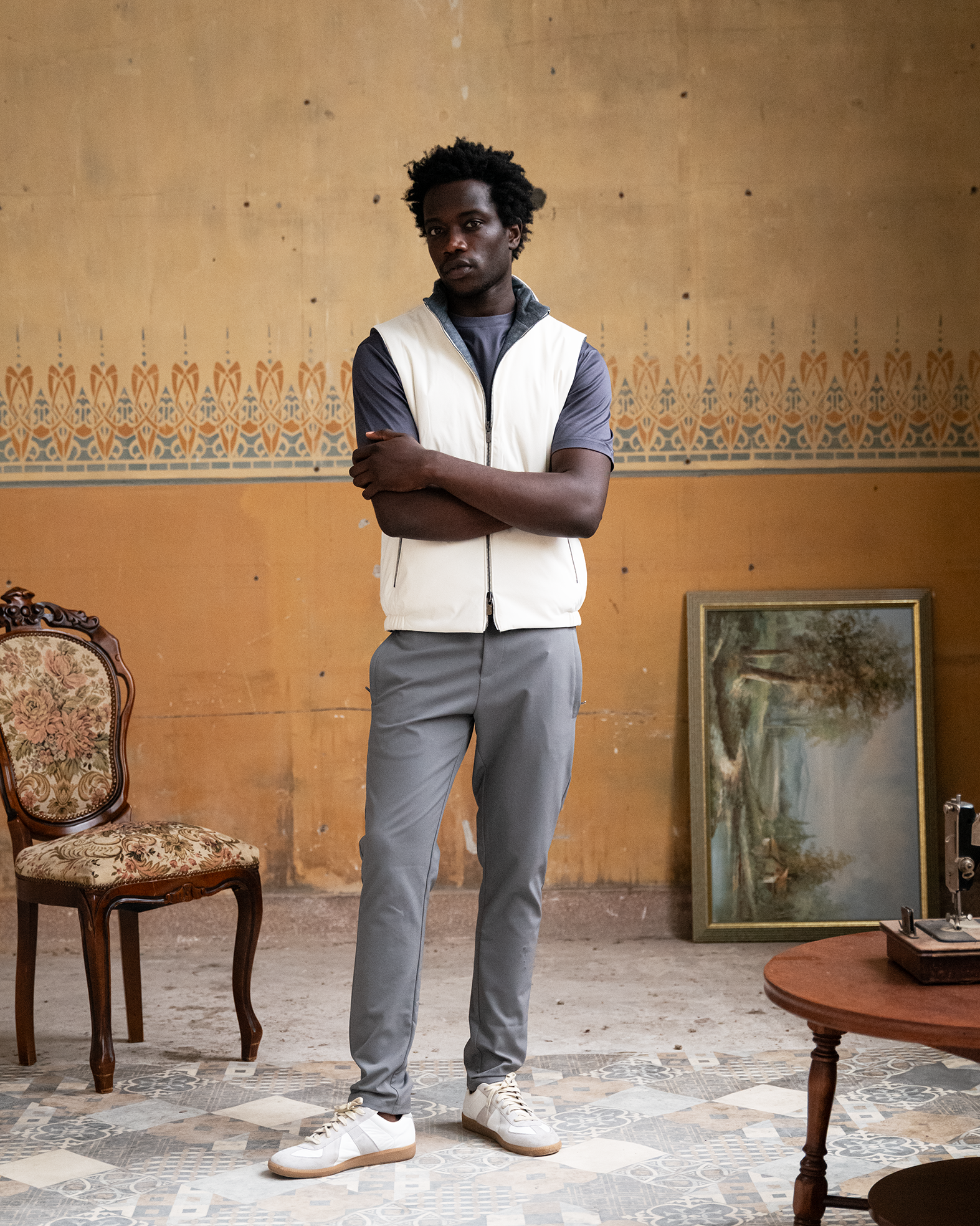 Man standing in a room with ornate wall patterns and vintage furniture.