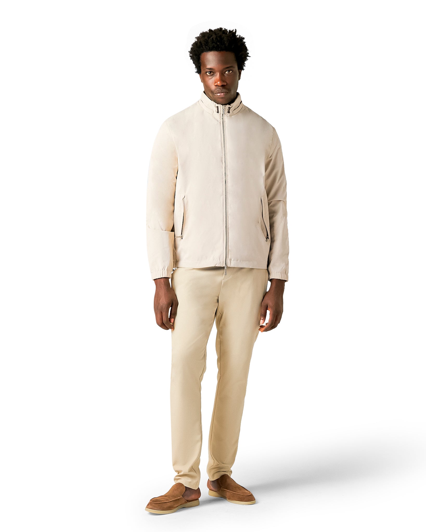 Man wearing a beige jacket and pants on a white background