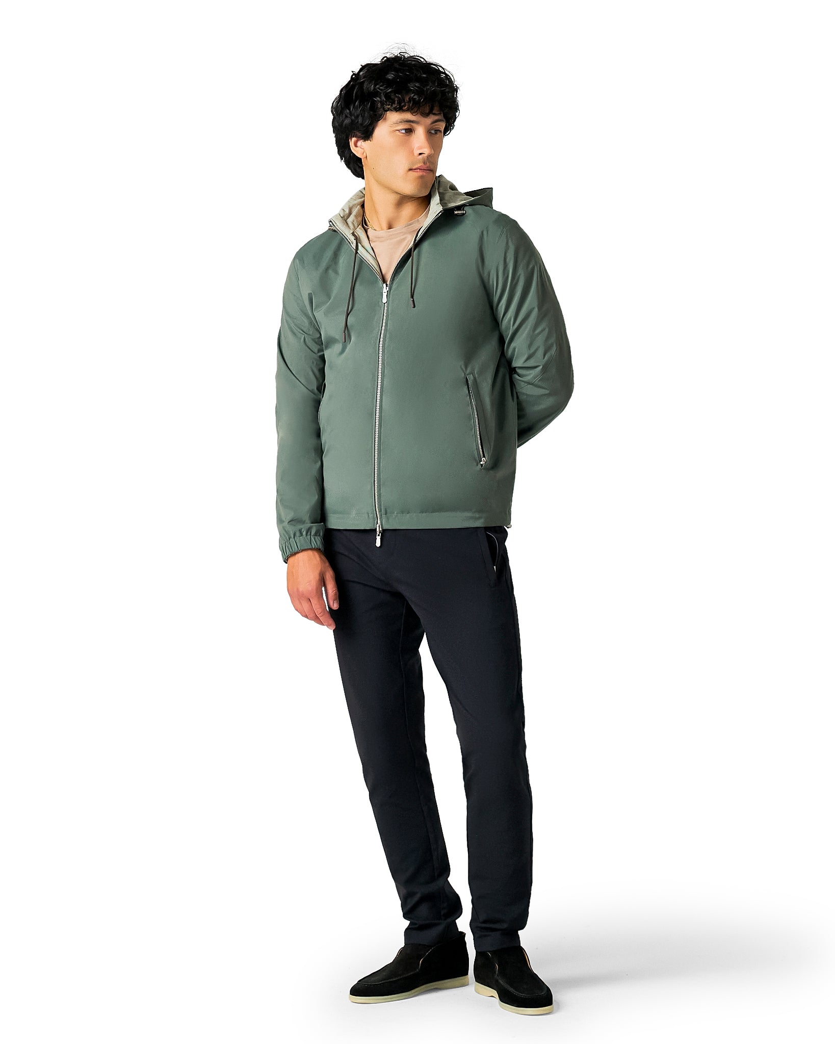 Man wearing a green jacket and black pants on a white background
