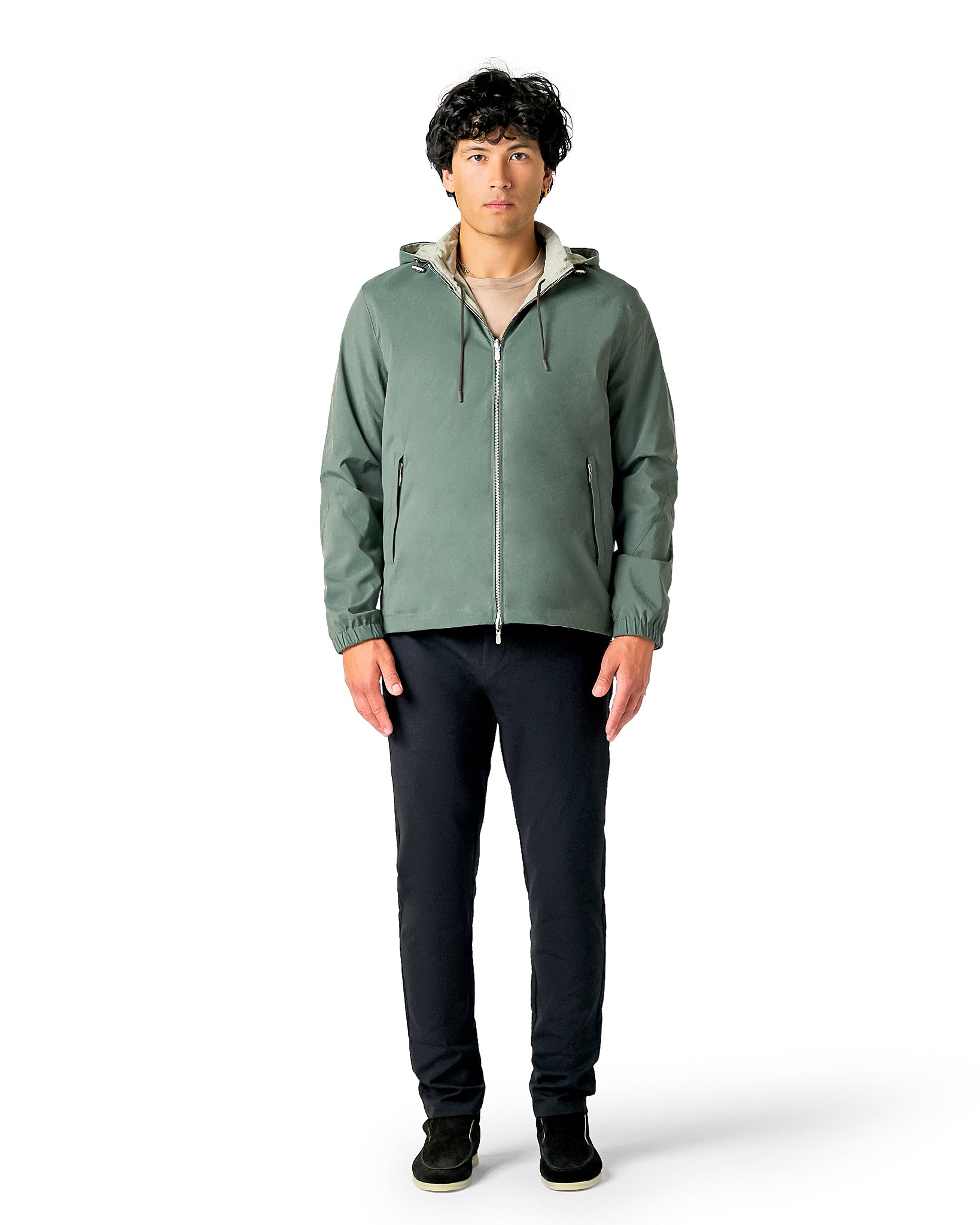 Man wearing a green jacket and black pants on a white background