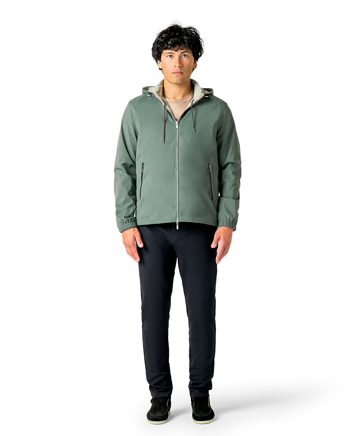 Man wearing a green jacket and black pants on a white background