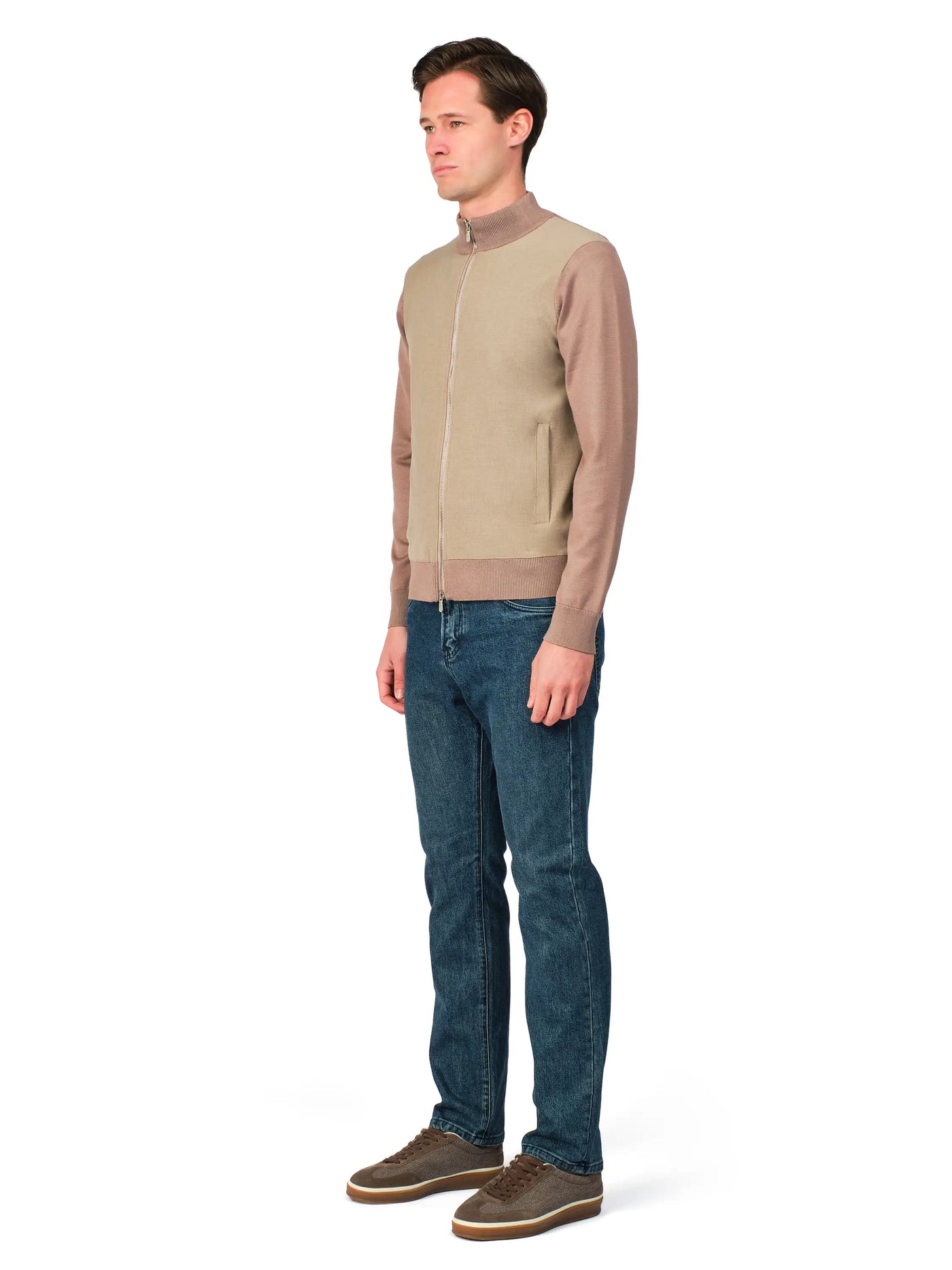 Man wearing a beige sweater and blue jeans on a white background