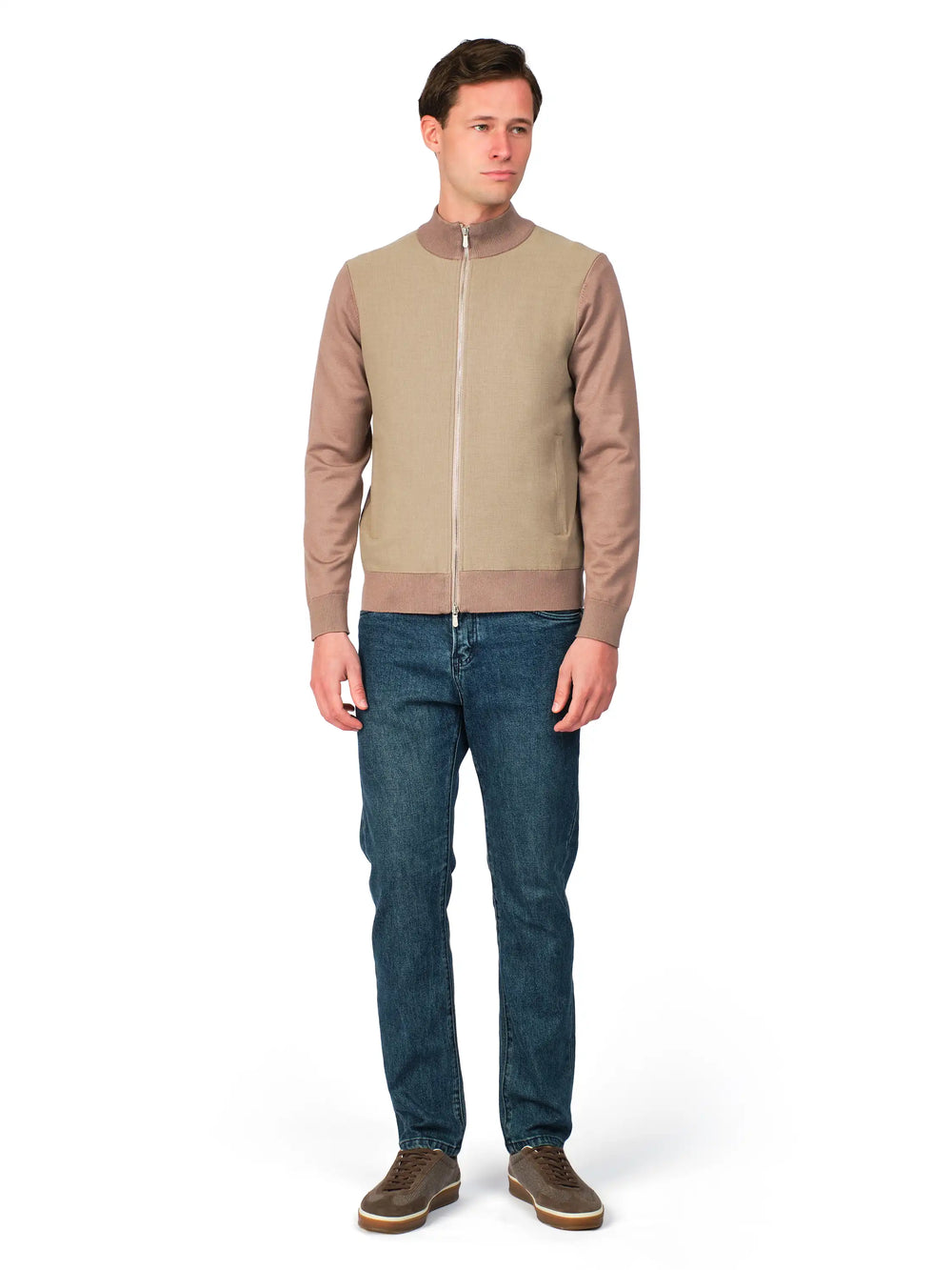 Man wearing a beige zip-up jacket and blue jeans on a white background