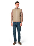 Man wearing a beige zip-up jacket and blue jeans on a white background