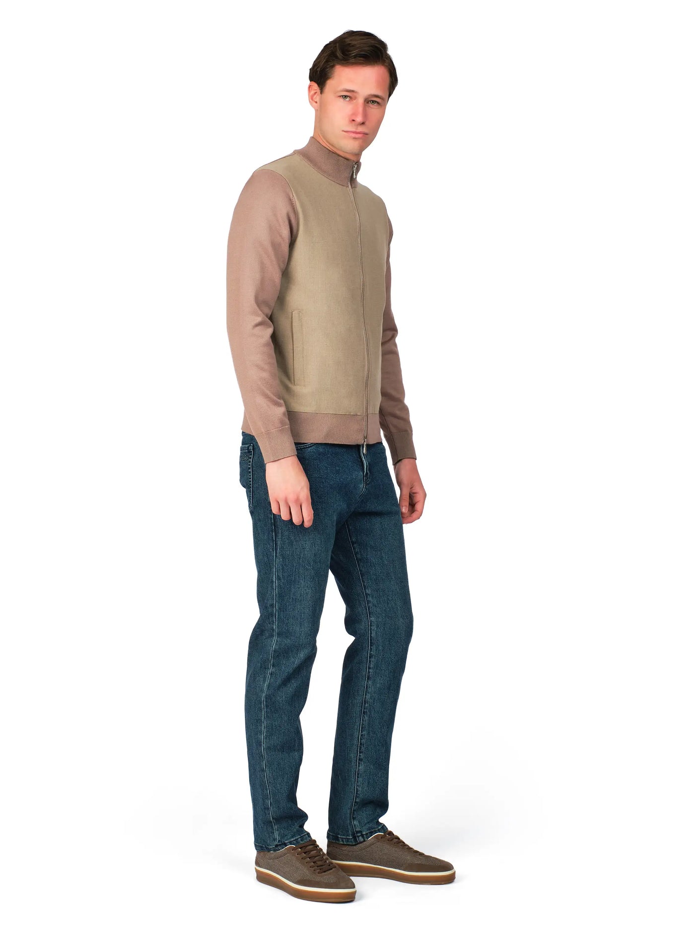 Man wearing a beige sweater and blue jeans on a white background