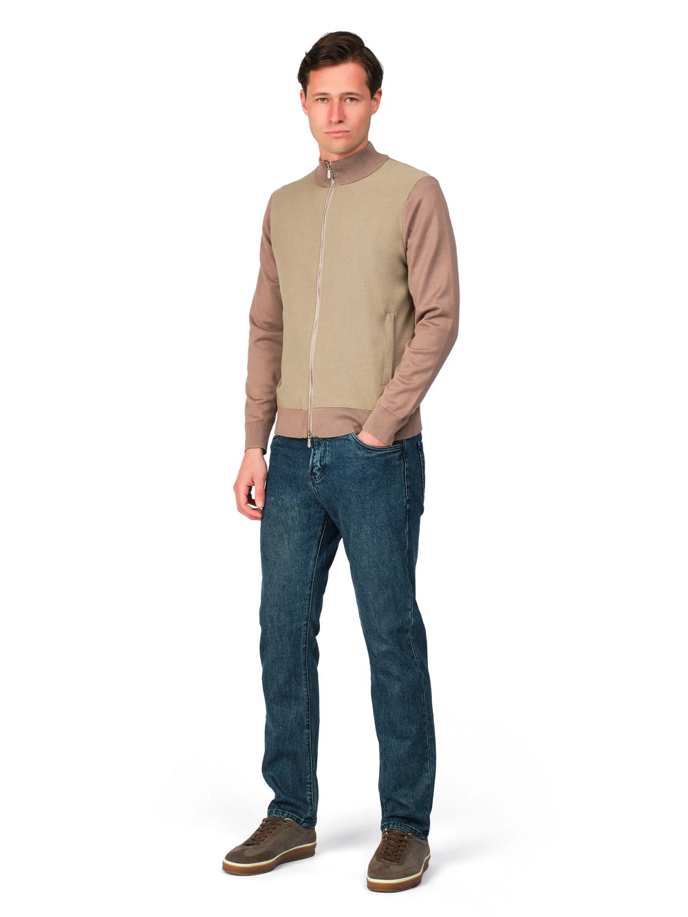 Man wearing a beige bomber jacket and blue jeans on a white background