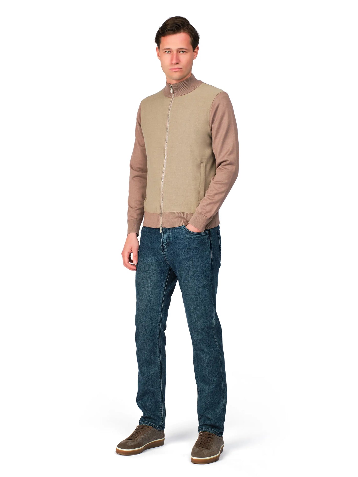 Man wearing a beige bomber jacket and blue jeans on a white background