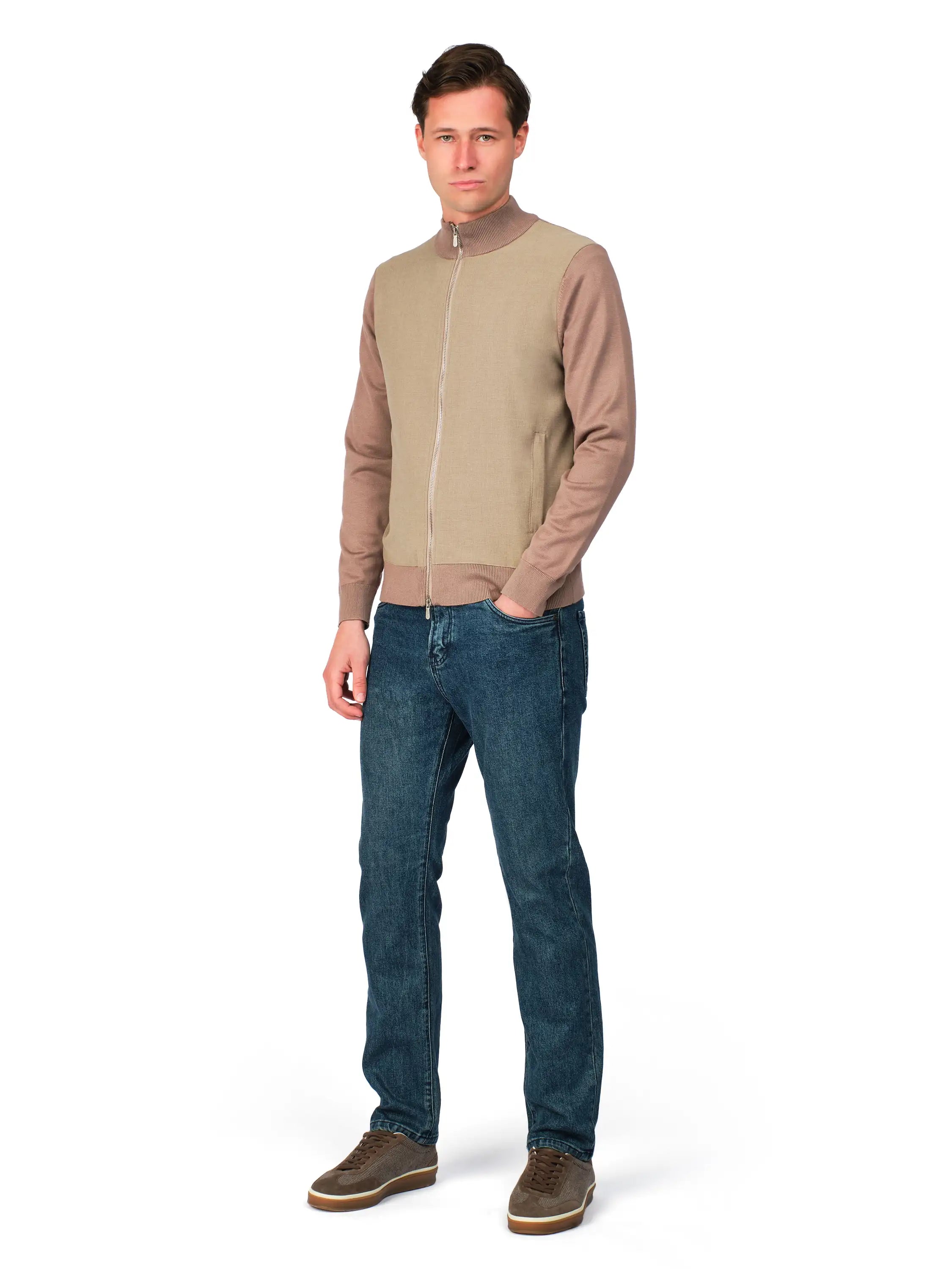 Man wearing a beige bomber jacket and blue jeans on a white background