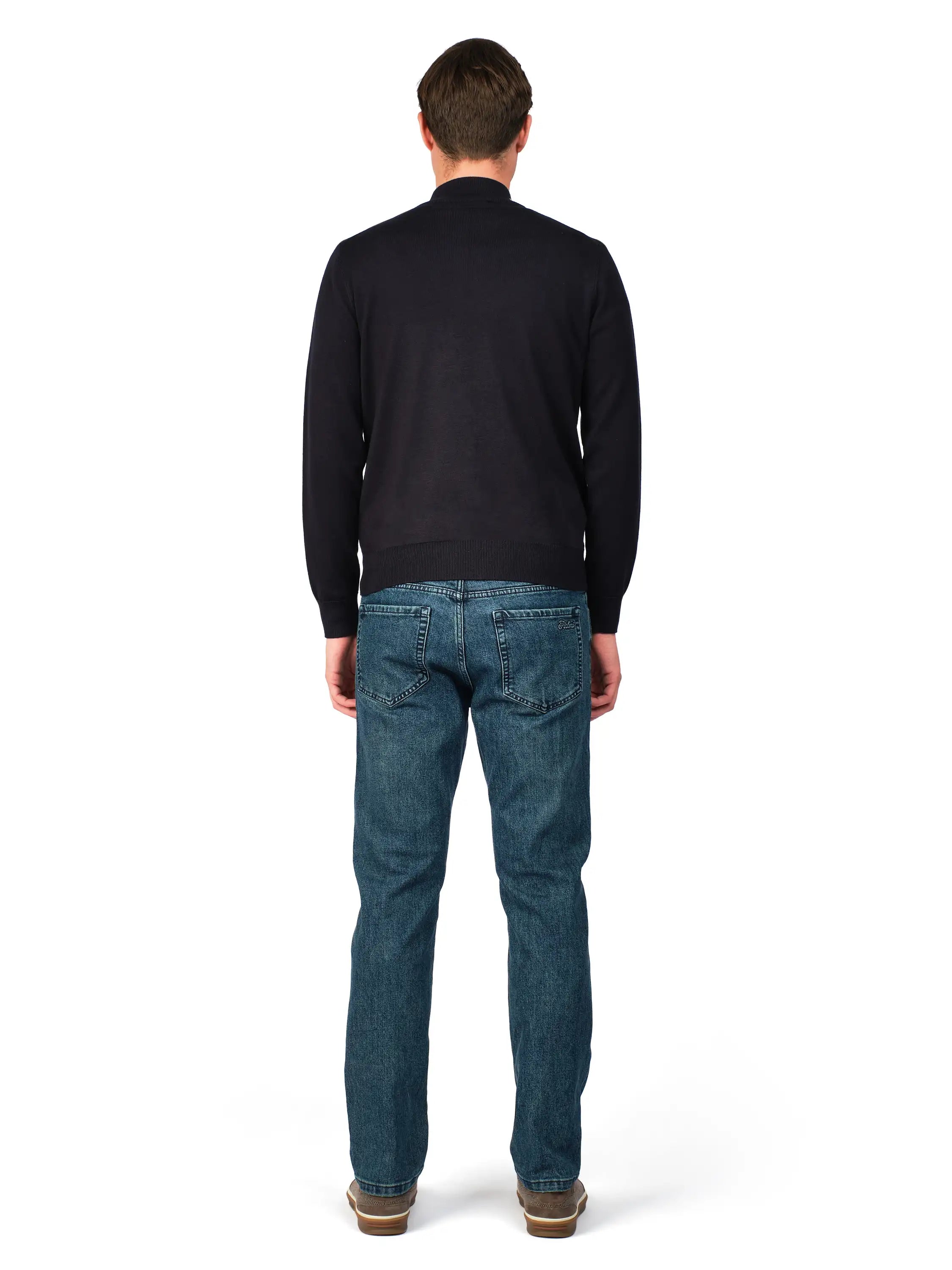 Man wearing a black sweater and blue jeans on a white background