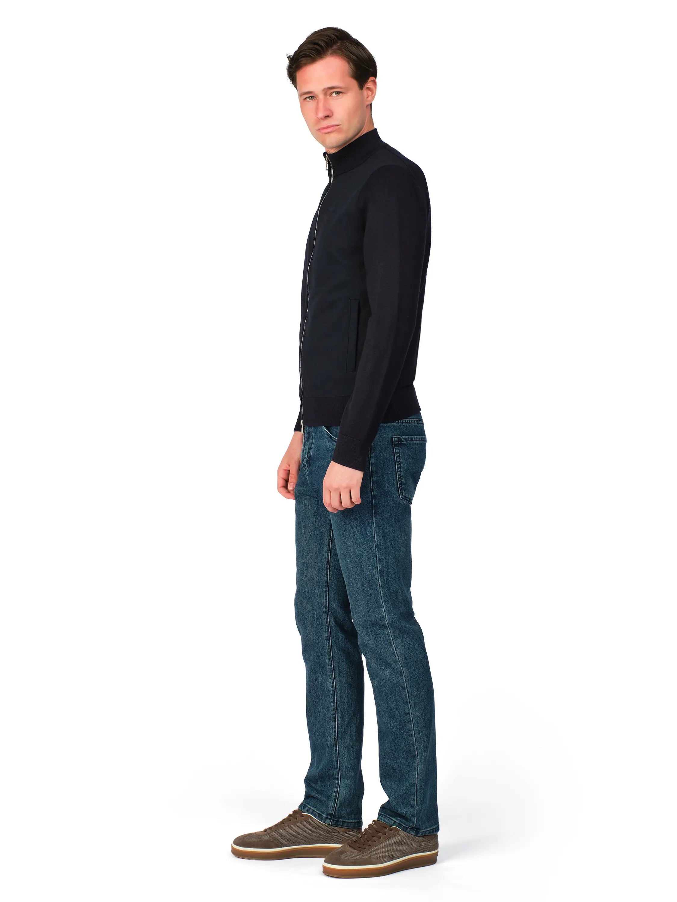 Man wearing a black turtleneck and blue jeans on a white background