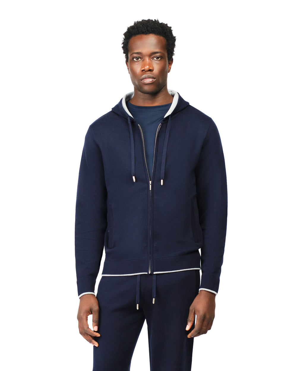 Man wearing a navy blue tracksuit with white accents on a white background