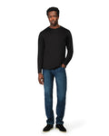 Man wearing a black long-sleeve shirt and blue jeans on a white background