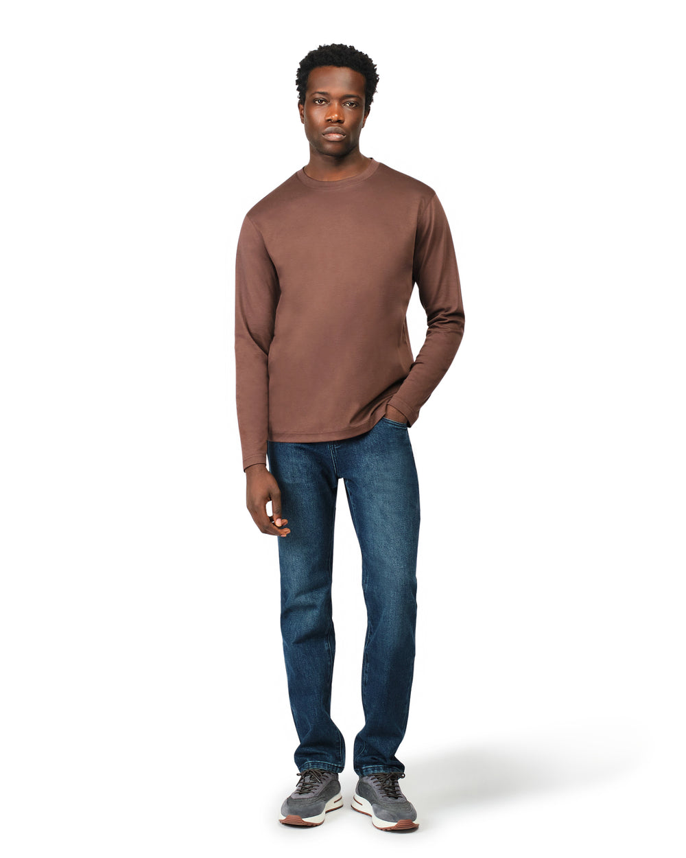 Man wearing a brown long-sleeve shirt and blue jeans on a white background