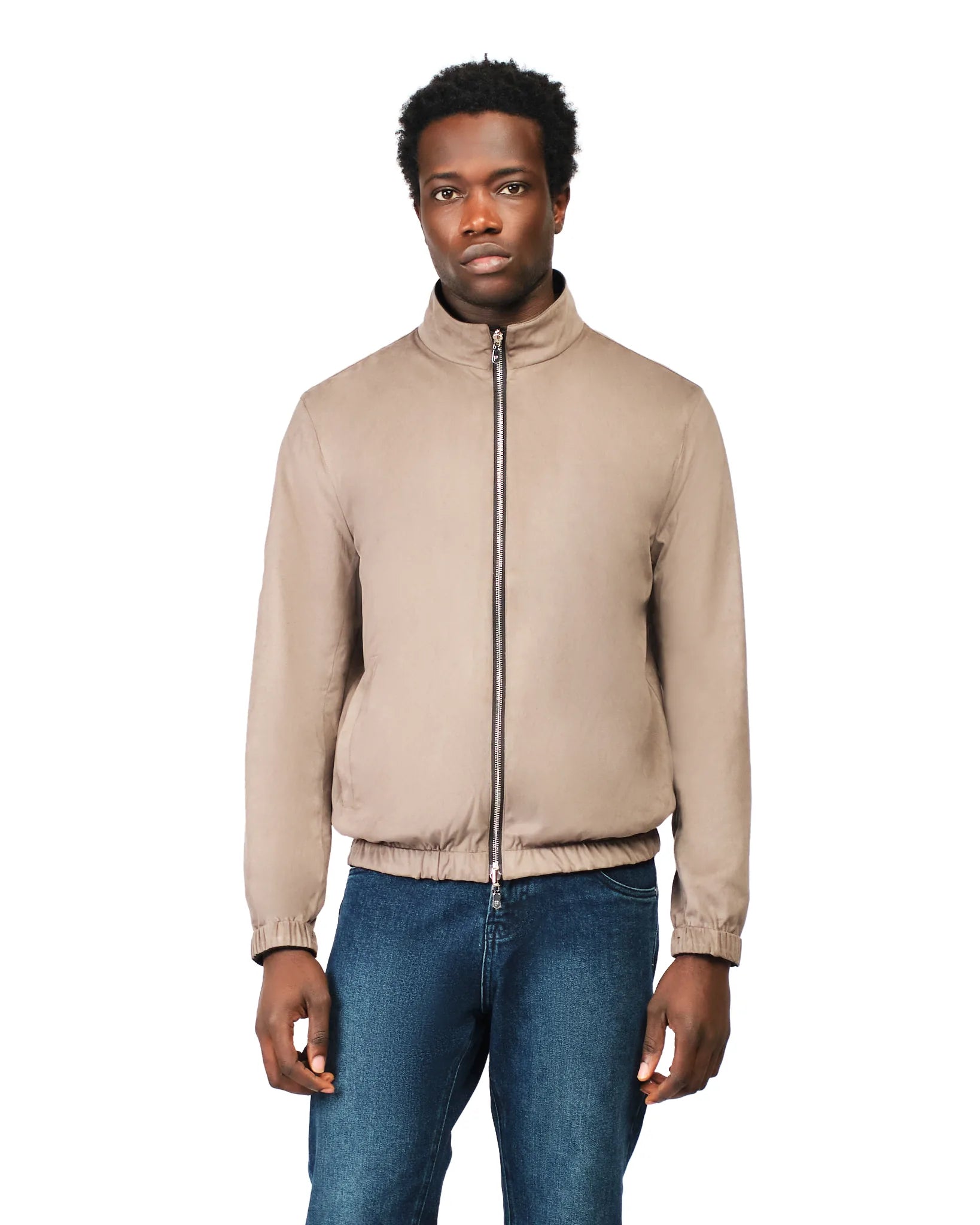 Man wearing a beige jacket and blue jeans on a white background