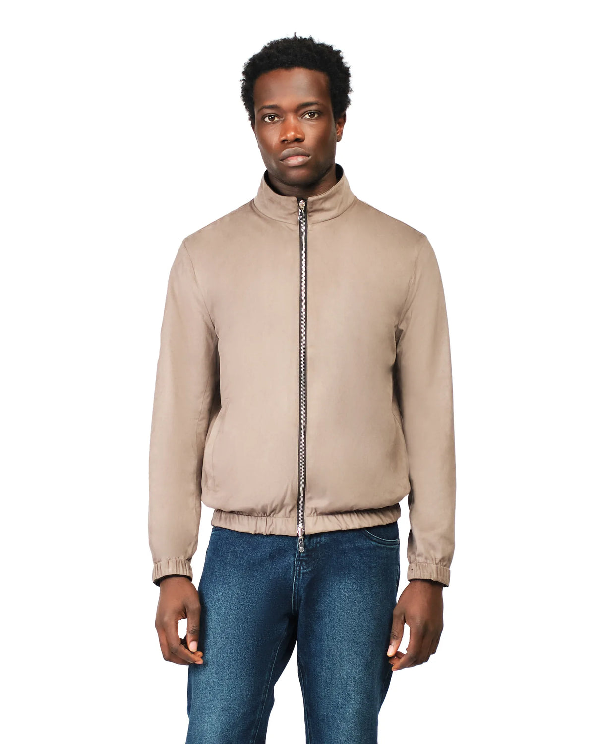 Man wearing a beige jacket and blue jeans on a white background