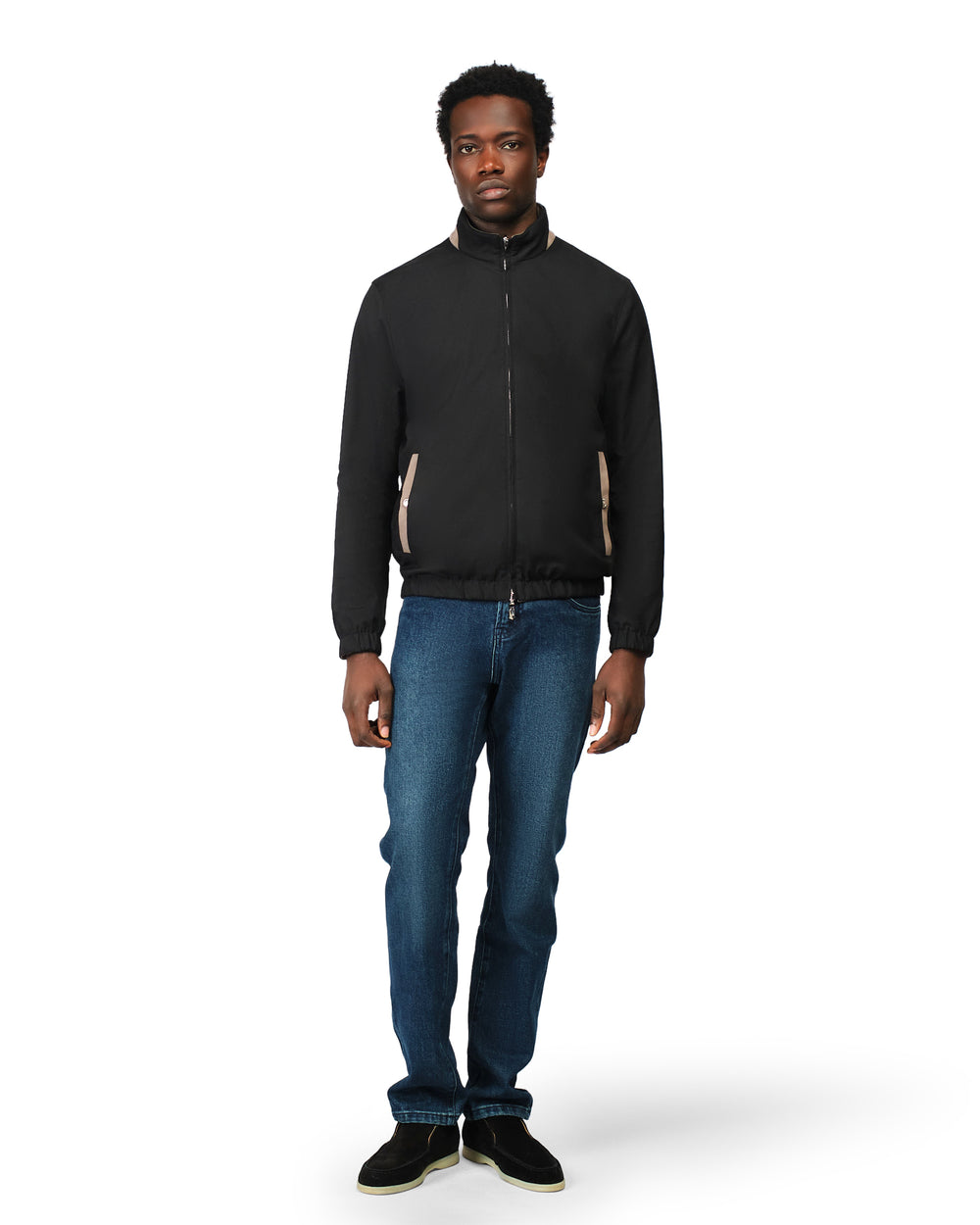 Man wearing a black jacket and blue jeans on a white background