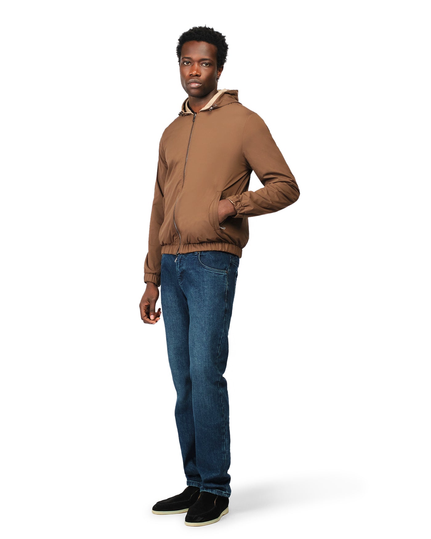 Man wearing a brown jacket and blue jeans on a white background