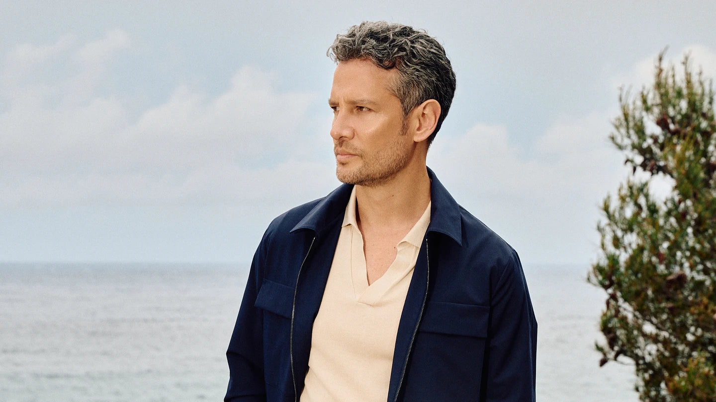 Man standing outdoors with a scenic background of water and sky