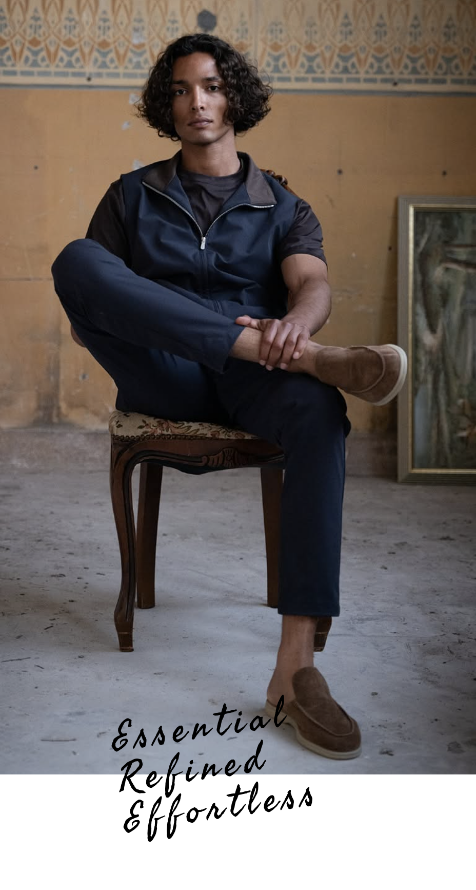 Person wearing a navy jumpsuit sitting on a wooden chair