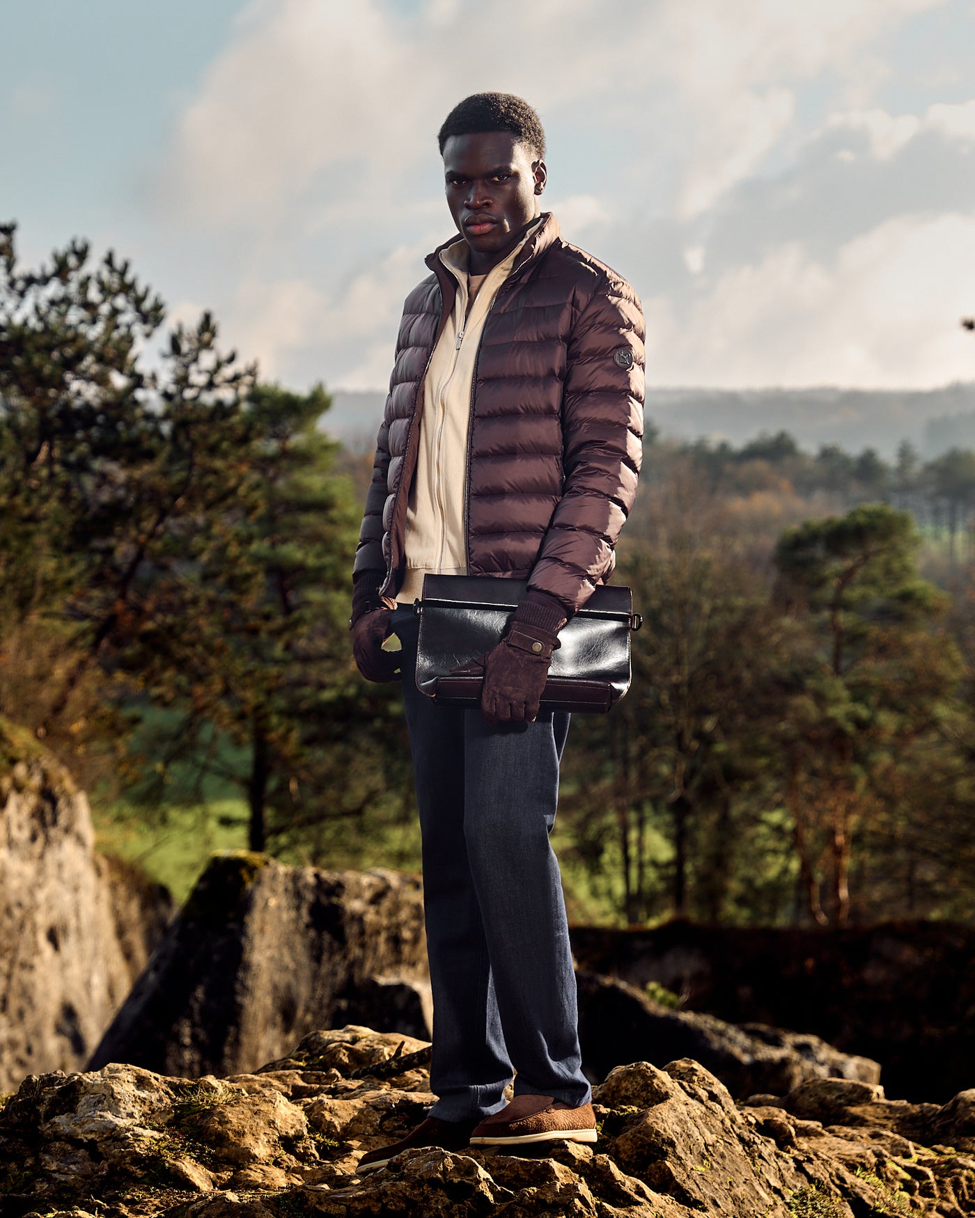 Man standing on a rocky outcrop with a scenic background