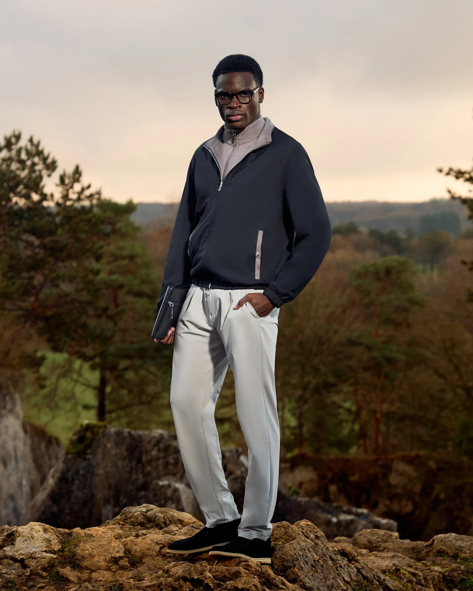 Man standing on a rocky outcrop with a natural landscape background