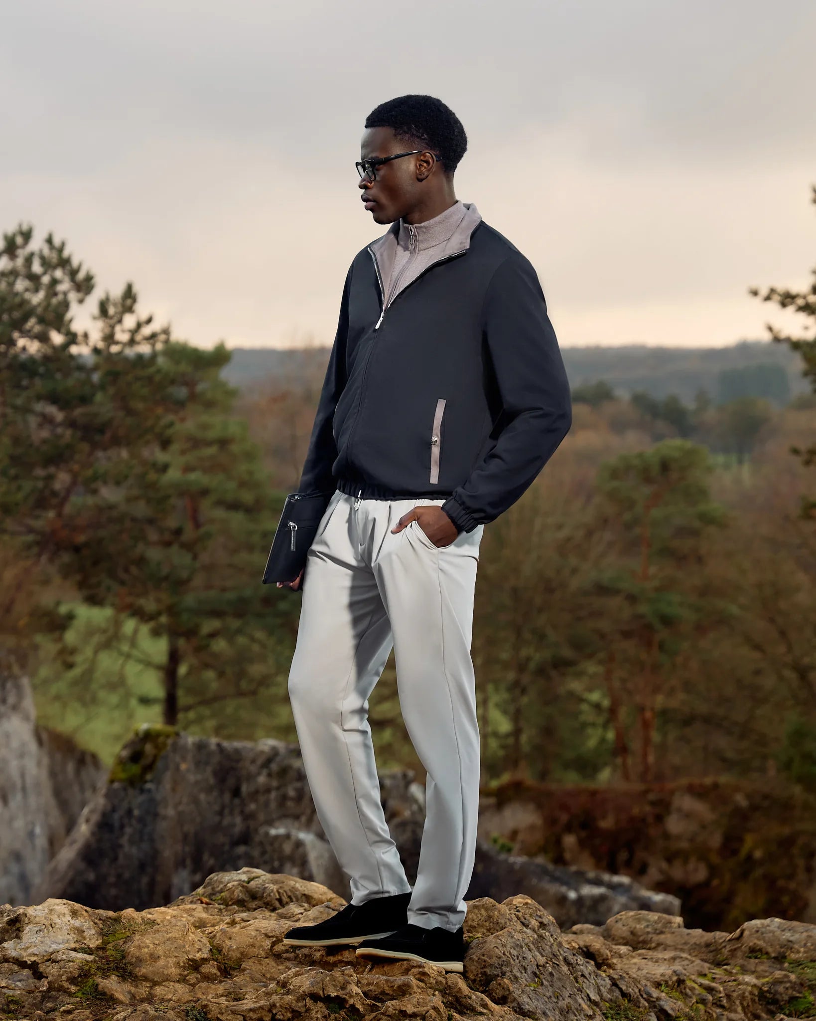 Man standing on a rocky outcrop with a scenic background